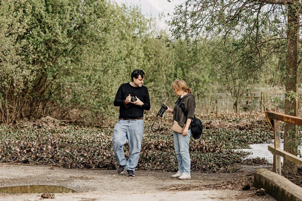 Two people standing on a wooden bridge having a conversation in nature.