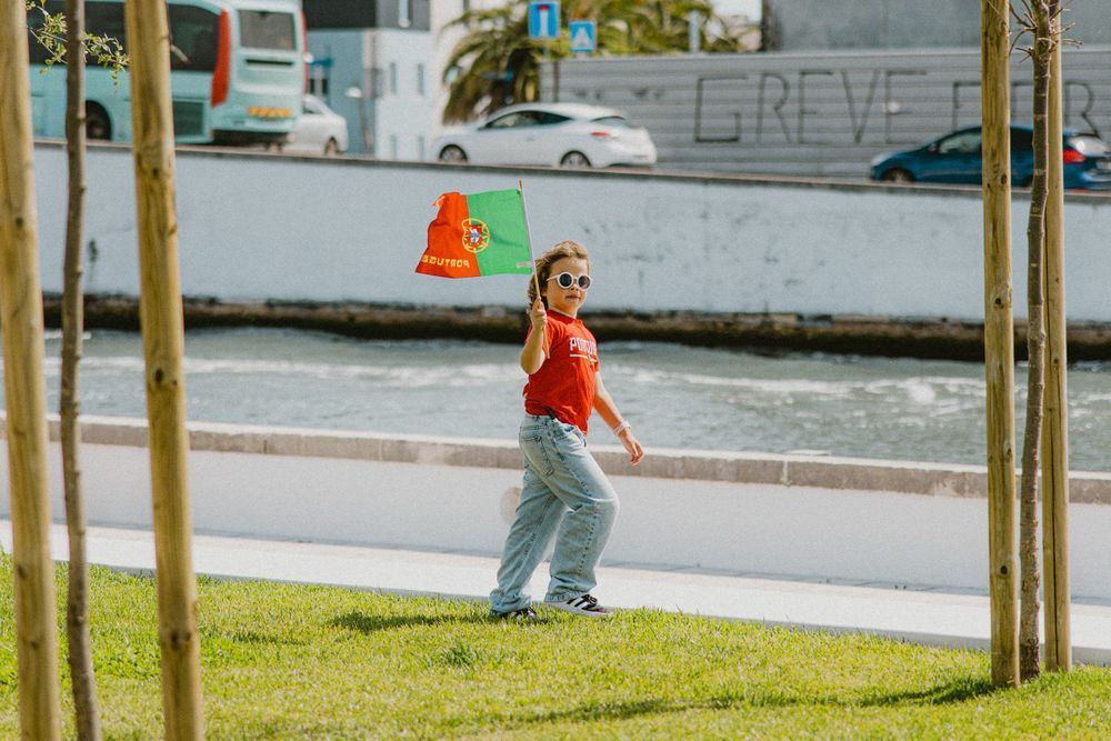 Child playing outdoors in casual wear near newly planted trees.