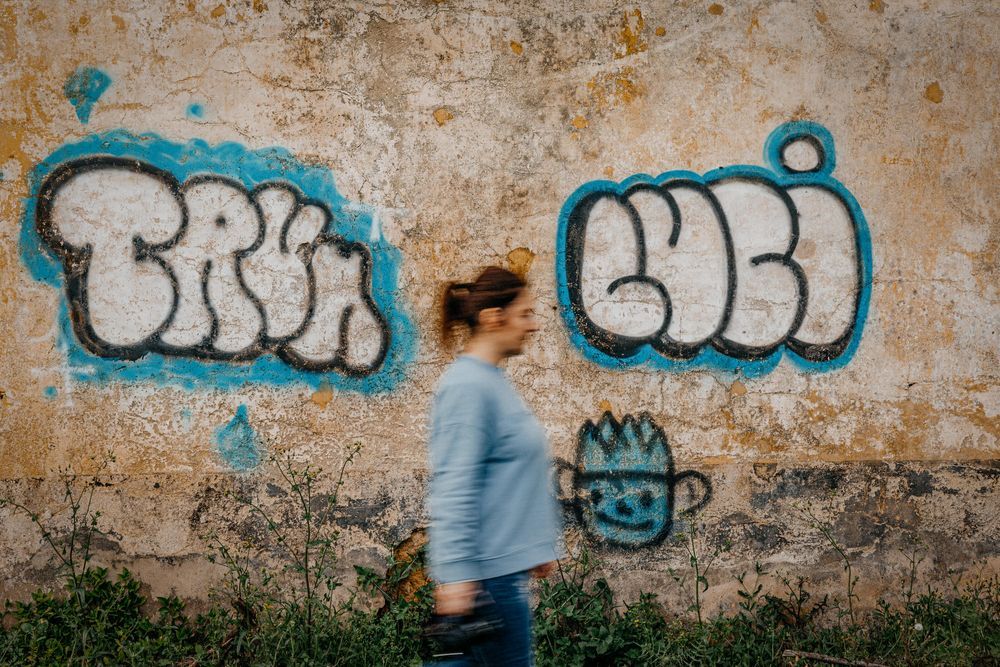 Blue graffiti art on weathered wall with motion blur in foreground.
