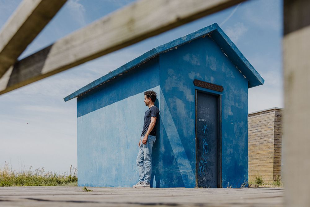 Small blue utility building against clear sky on wooden boardwalk.