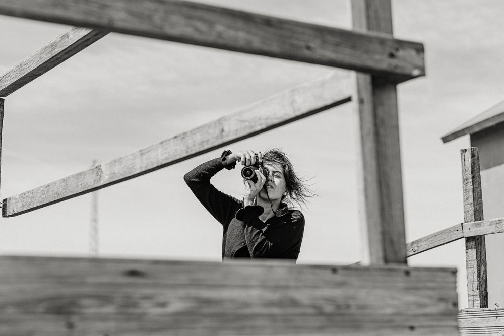 Figure looking into distance through wooden structure frame in black and white.