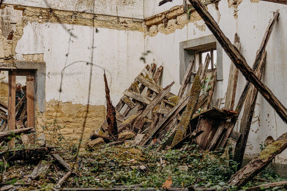 Decaying interior of abandoned building with broken wooden debris and weathered walls.