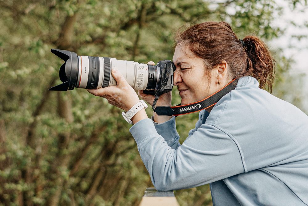 Photographer using professional camera with telephoto lens to capture nature shots.