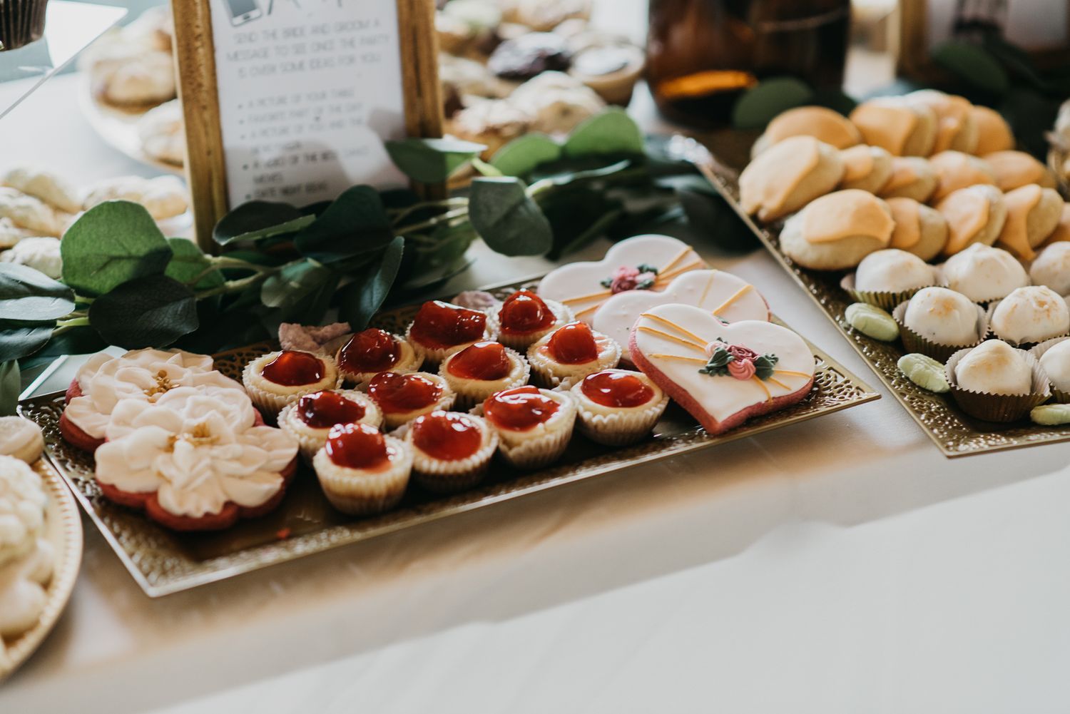 cherry filled cookies next to heart shaped sugar cookies with lace details in the frosting