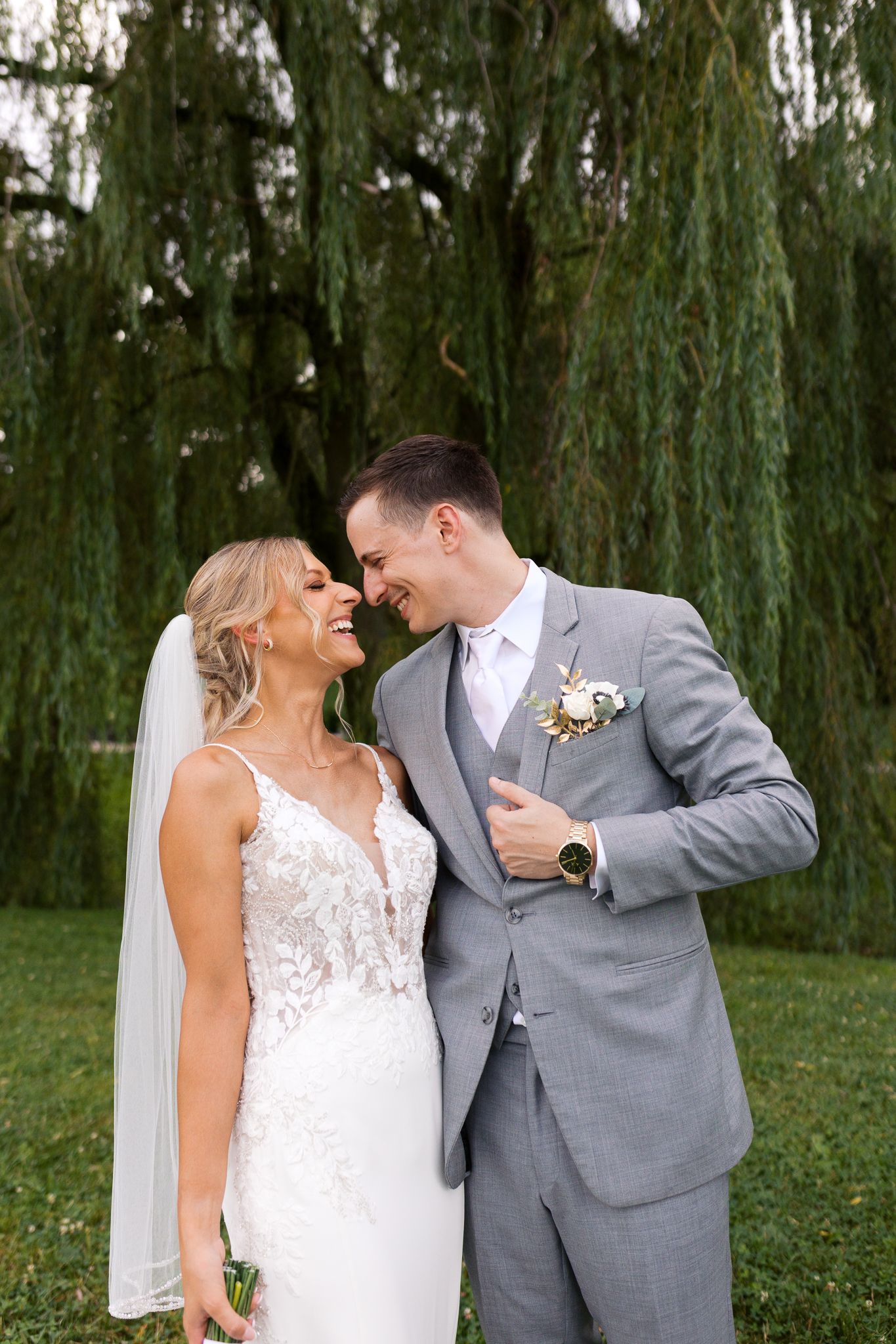 man holding on to his suit lapel while laughing with his bride