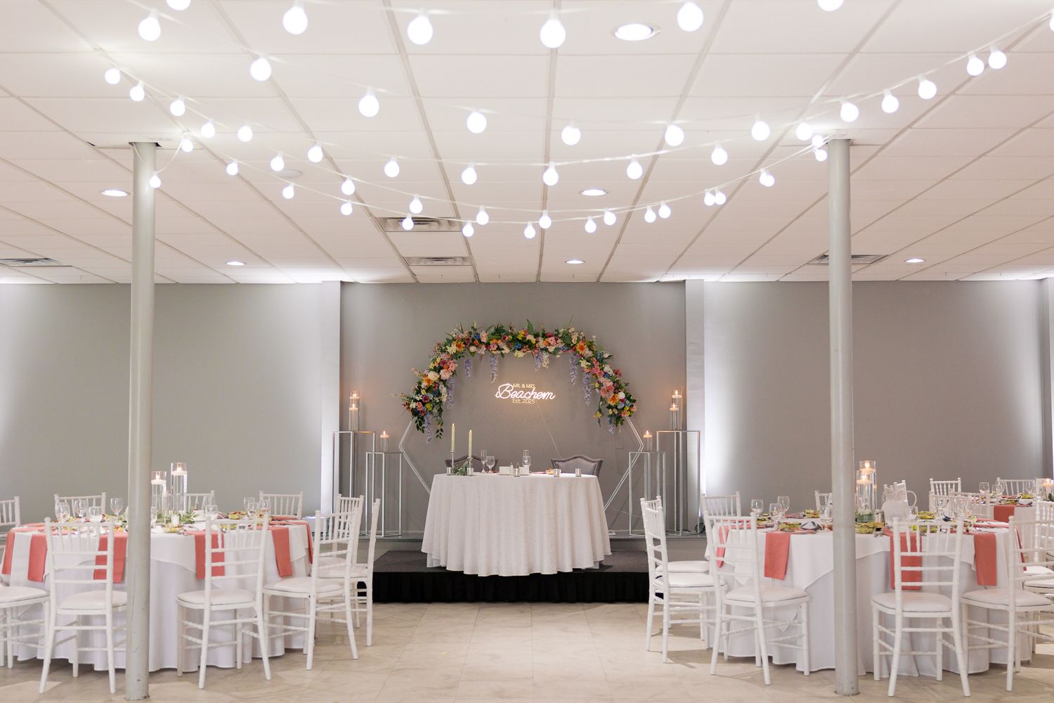 bride and groom sweetheart table with parent tables set up in reception hall with twinkling lights