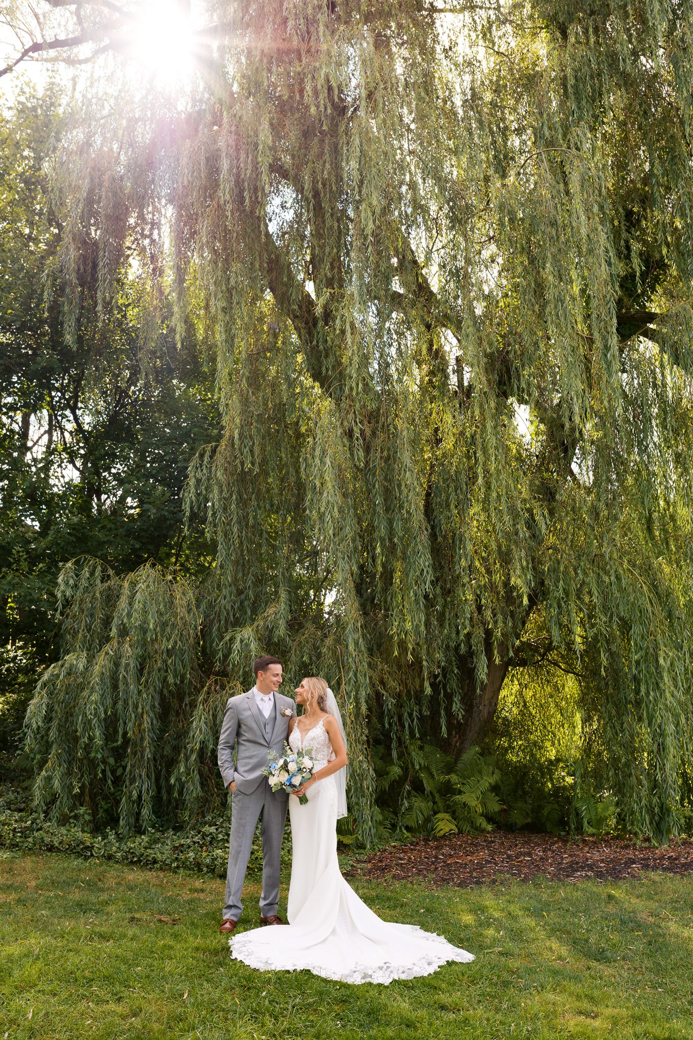 bride and groom staring lovingly at each other underneath a giant willow tree
