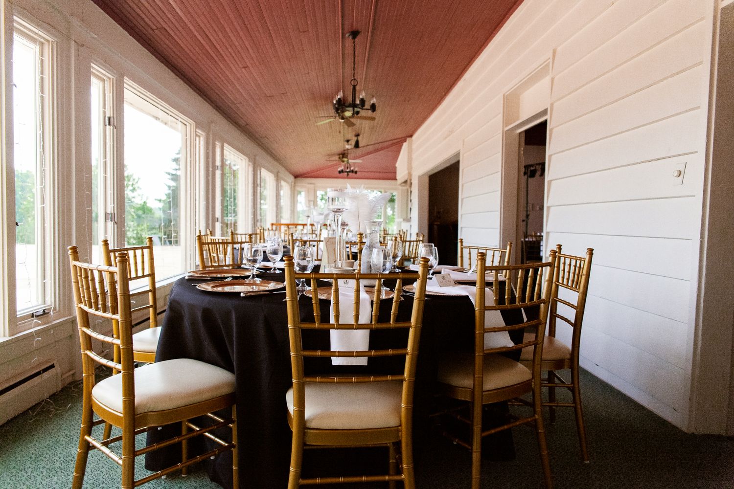 gold wedding chairs with white cushions set around round tables with black tablecloths