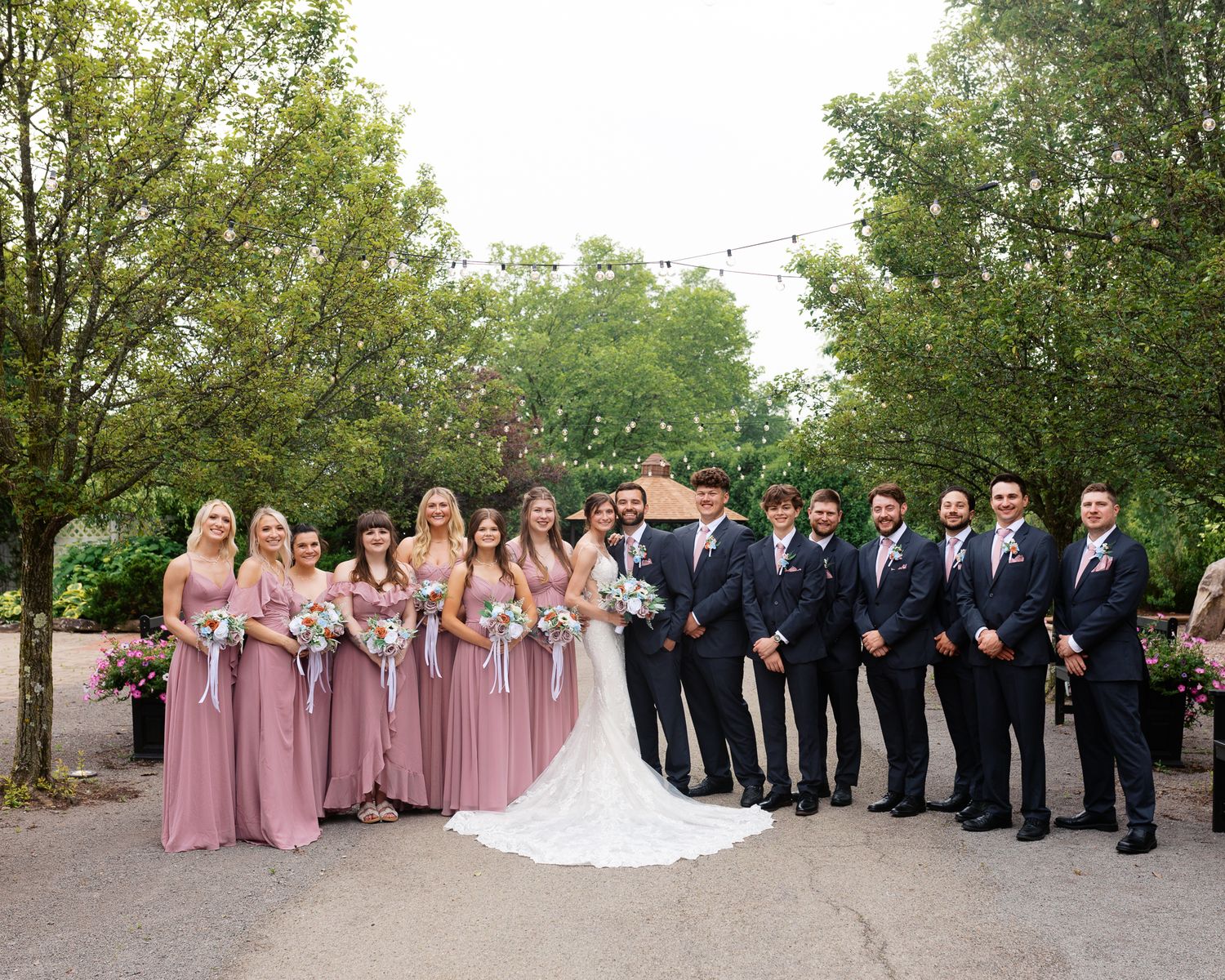 large bridal party shot with bridesmaids in light pink dresses and men in dark suits in the courtyard of The Atrium in Butler PA