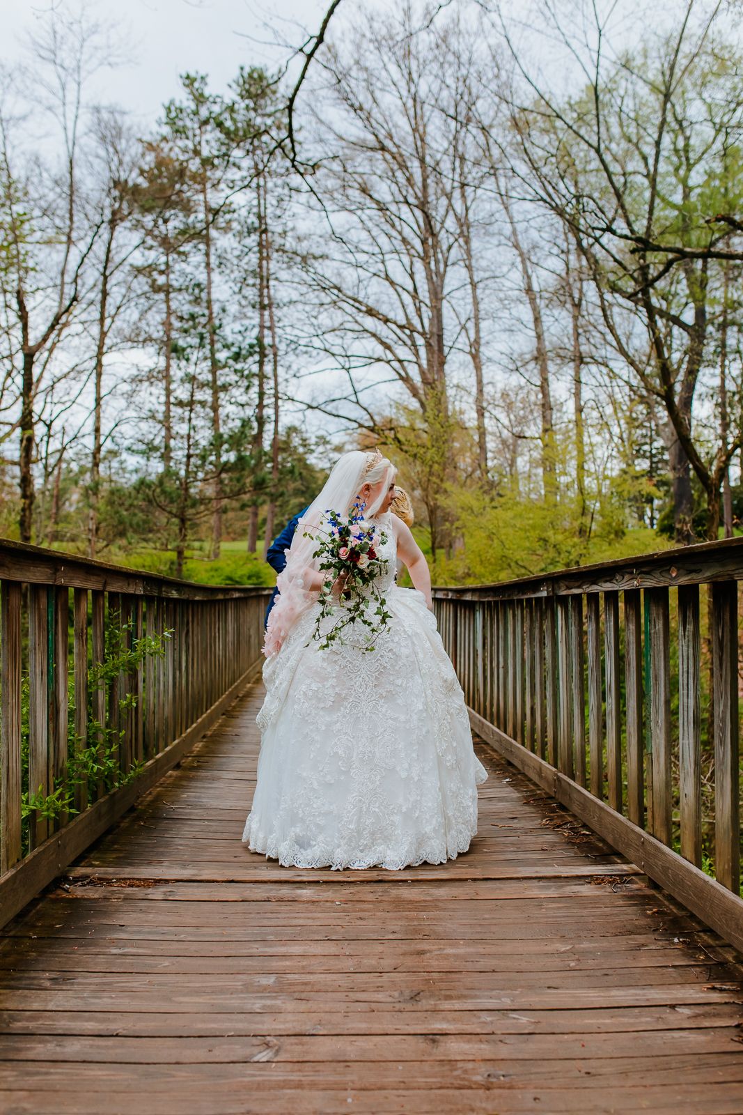 bride standing on wooden bridge in the woods