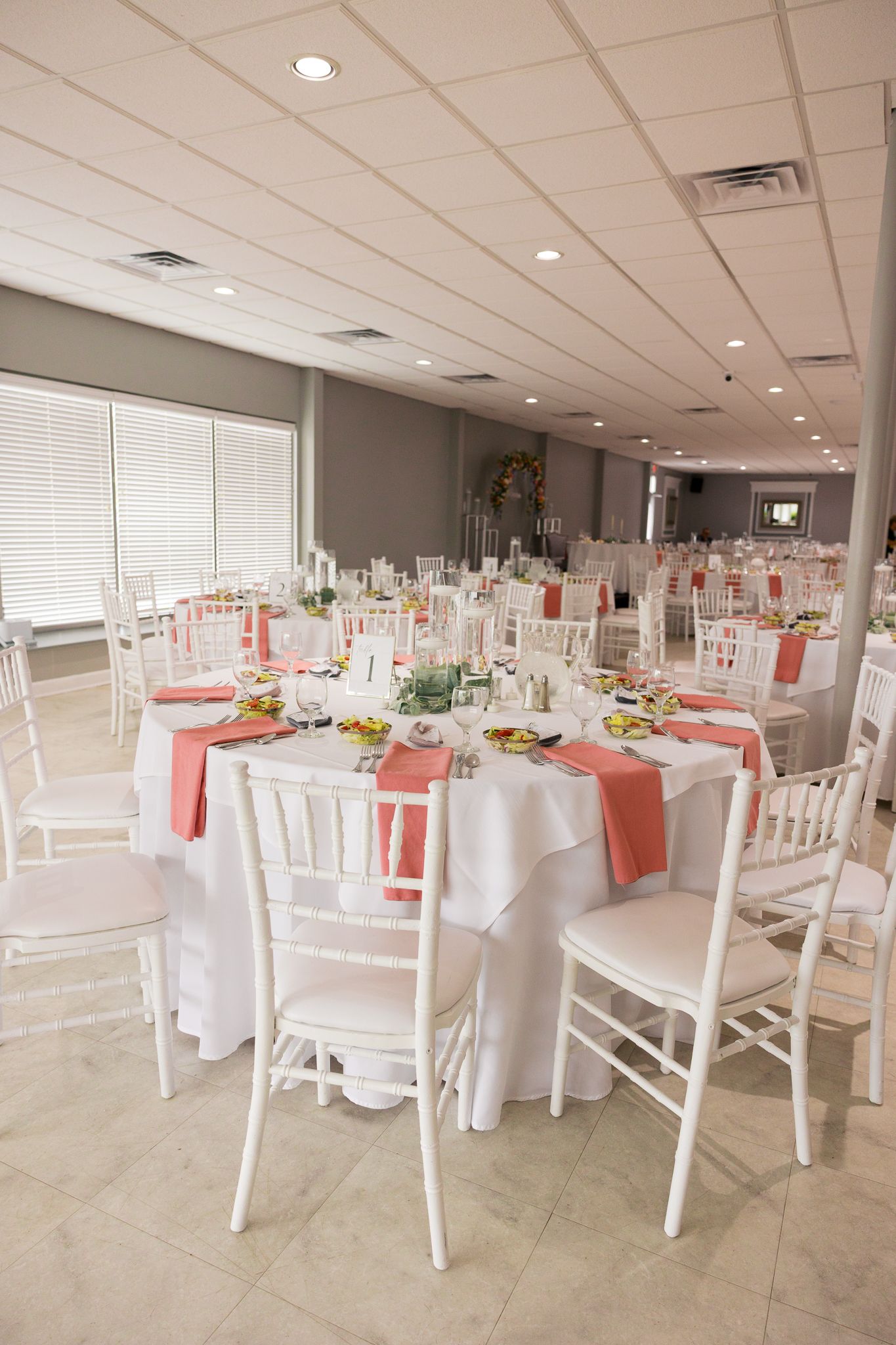 reception tables with white chairs, white tablecloths and pink napkins