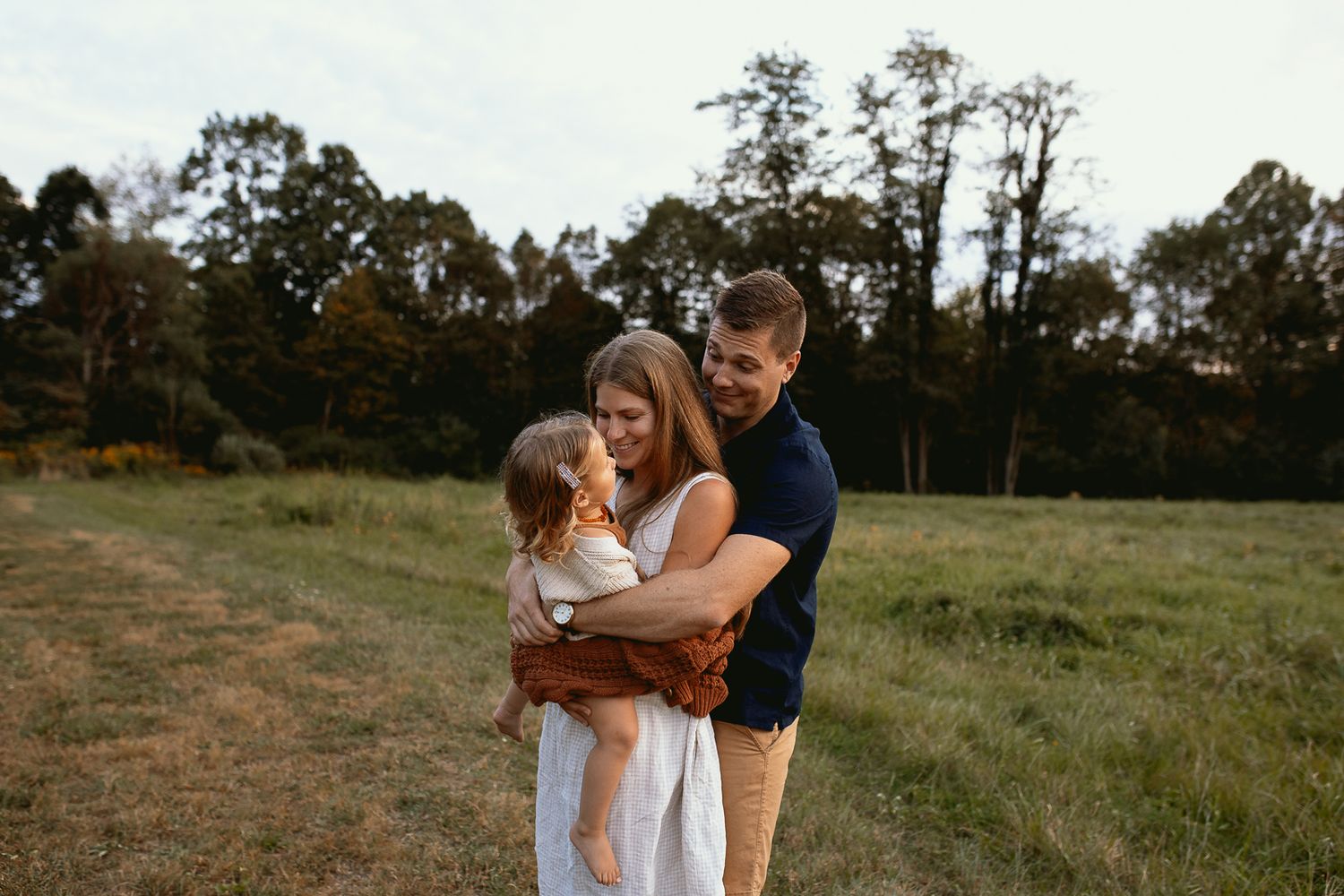 man holding woman while she holds their child in comfy, summer outfits
