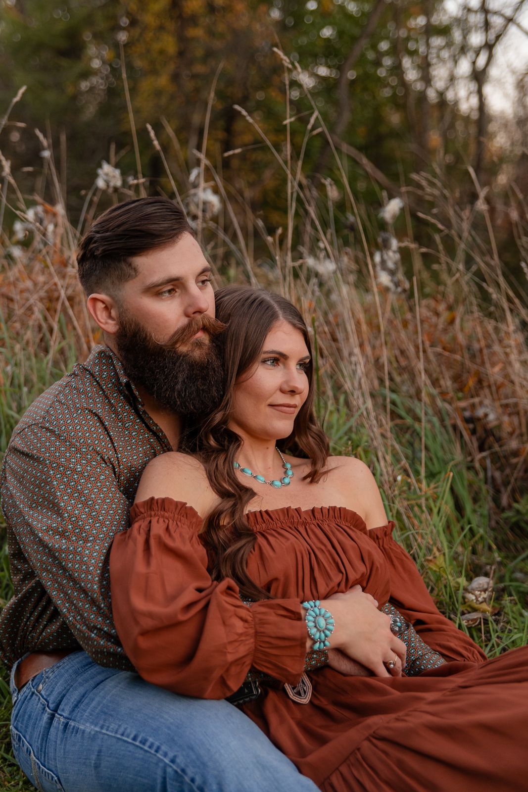 man and woman sitting on the ground together in a burgundy and olive coordinating outfit