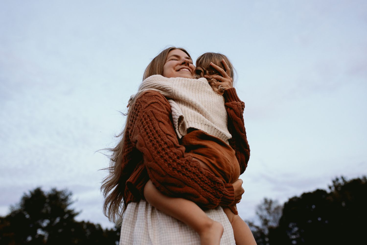 woman holding child in white and brown outfits