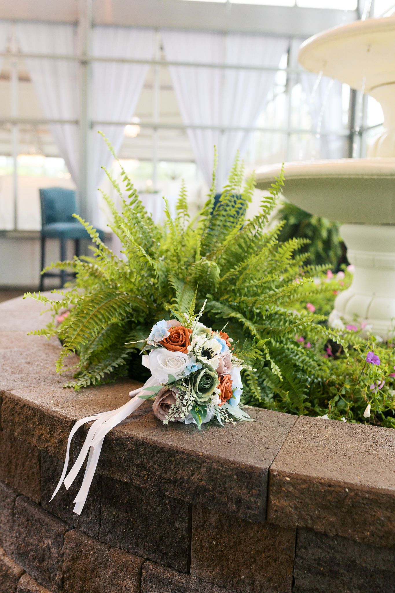 bouquet laid next to indoor fountain with green ferns in the background
