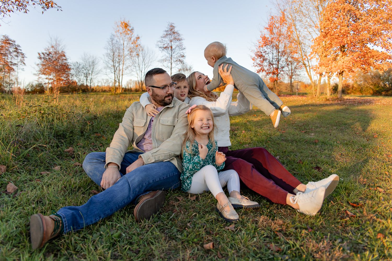 family of five sitting on the ground playing with each other