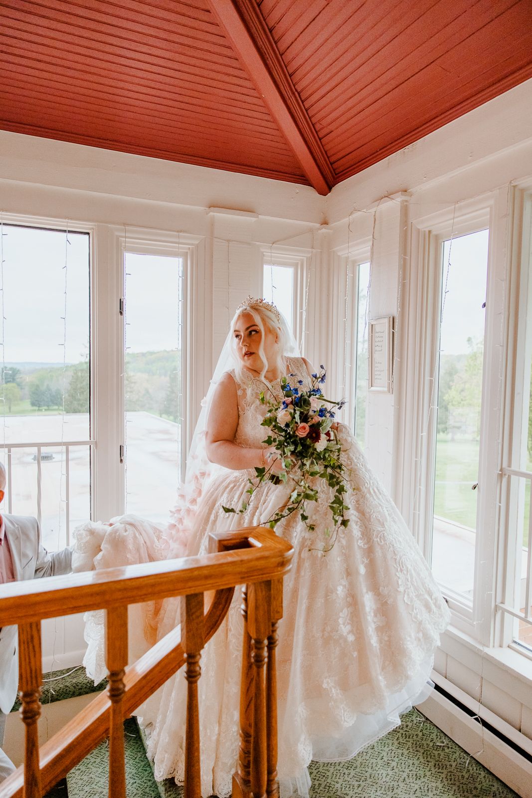 bride walking up steps while glancing over her shoulder and holding her gown so she doesn't trip