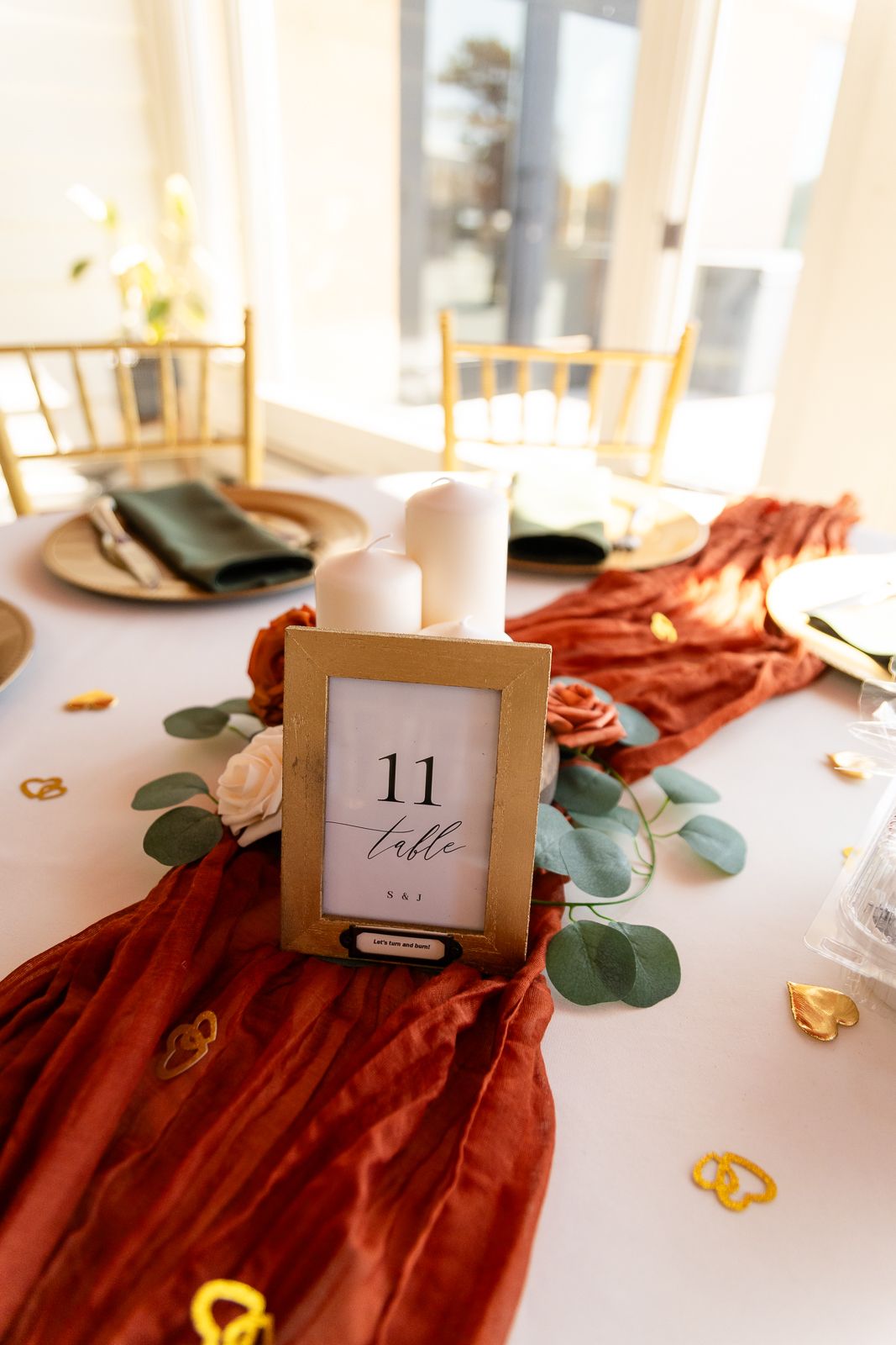 table number 11 in a gold frame sitting on table with candles and greenery