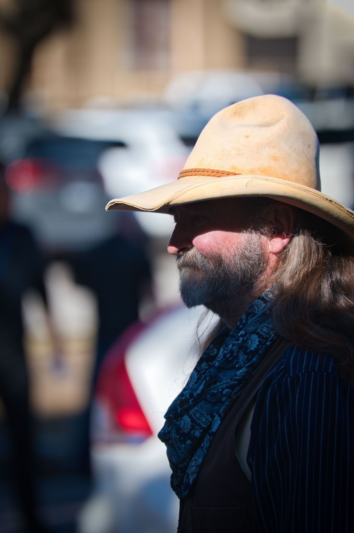 Side profile of cowboy wearing light colored hat and dark clothing.