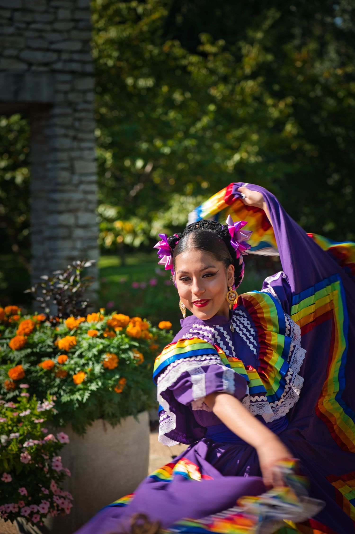 Dancer in colorful traditional Mexican dress twirling among marigold flowers.