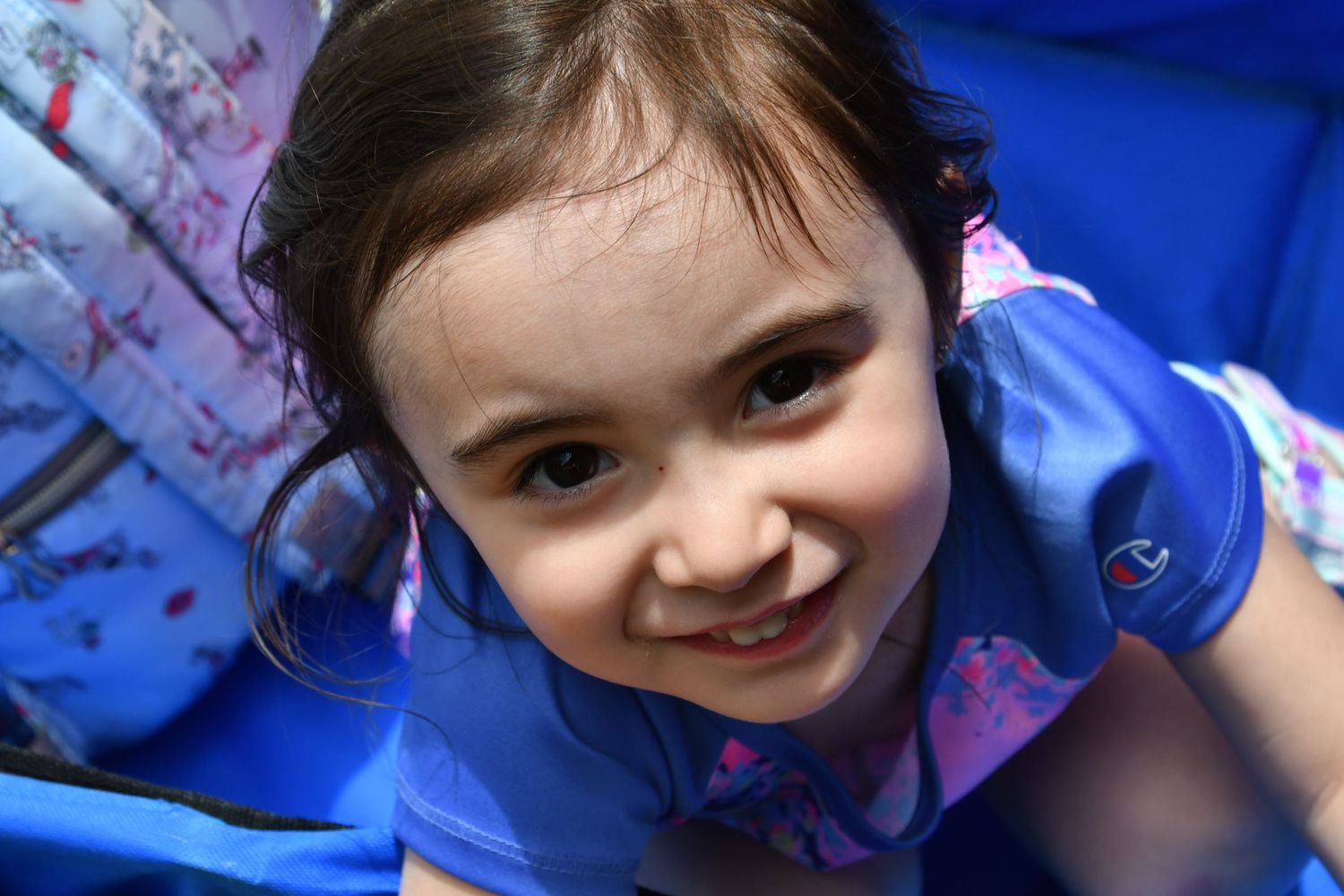 Child in blue dress smiling brightly at camera.