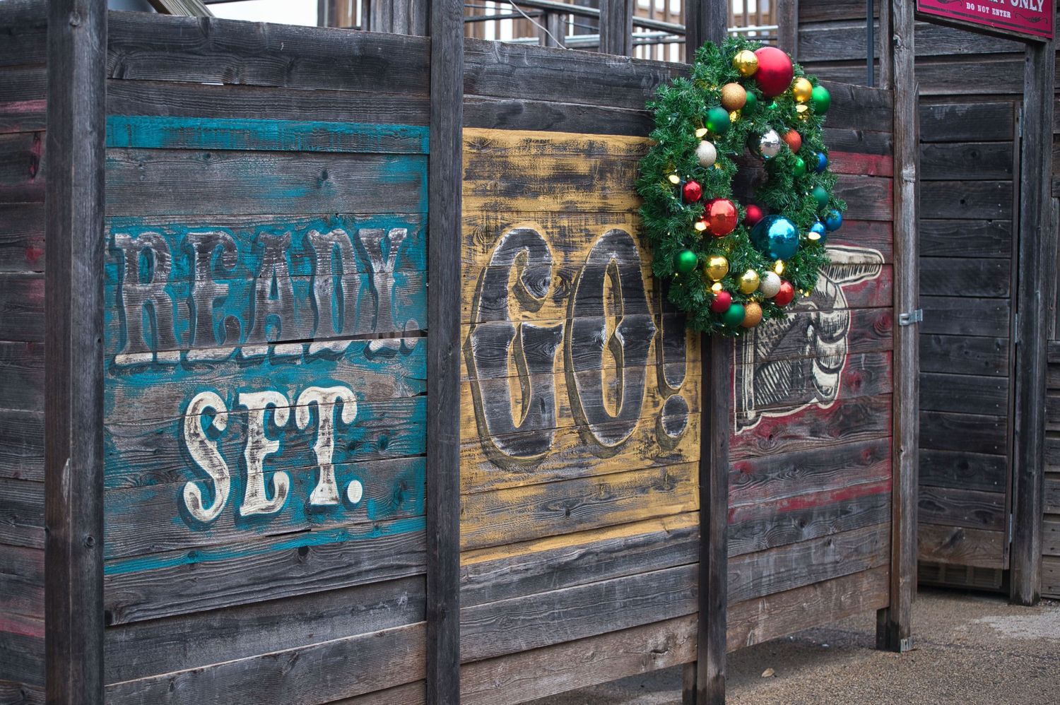 Rustic wooden wall with vintage signage and Christmas wreath decoration.