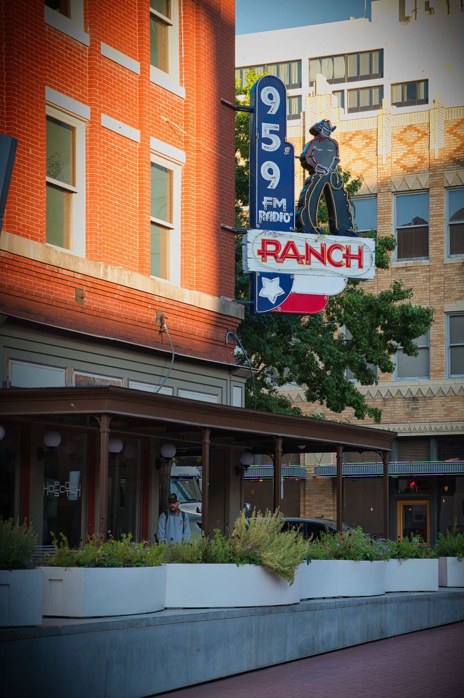Vintage brick building facade with a ranch sign and cowboy silhouette in an urban setting.