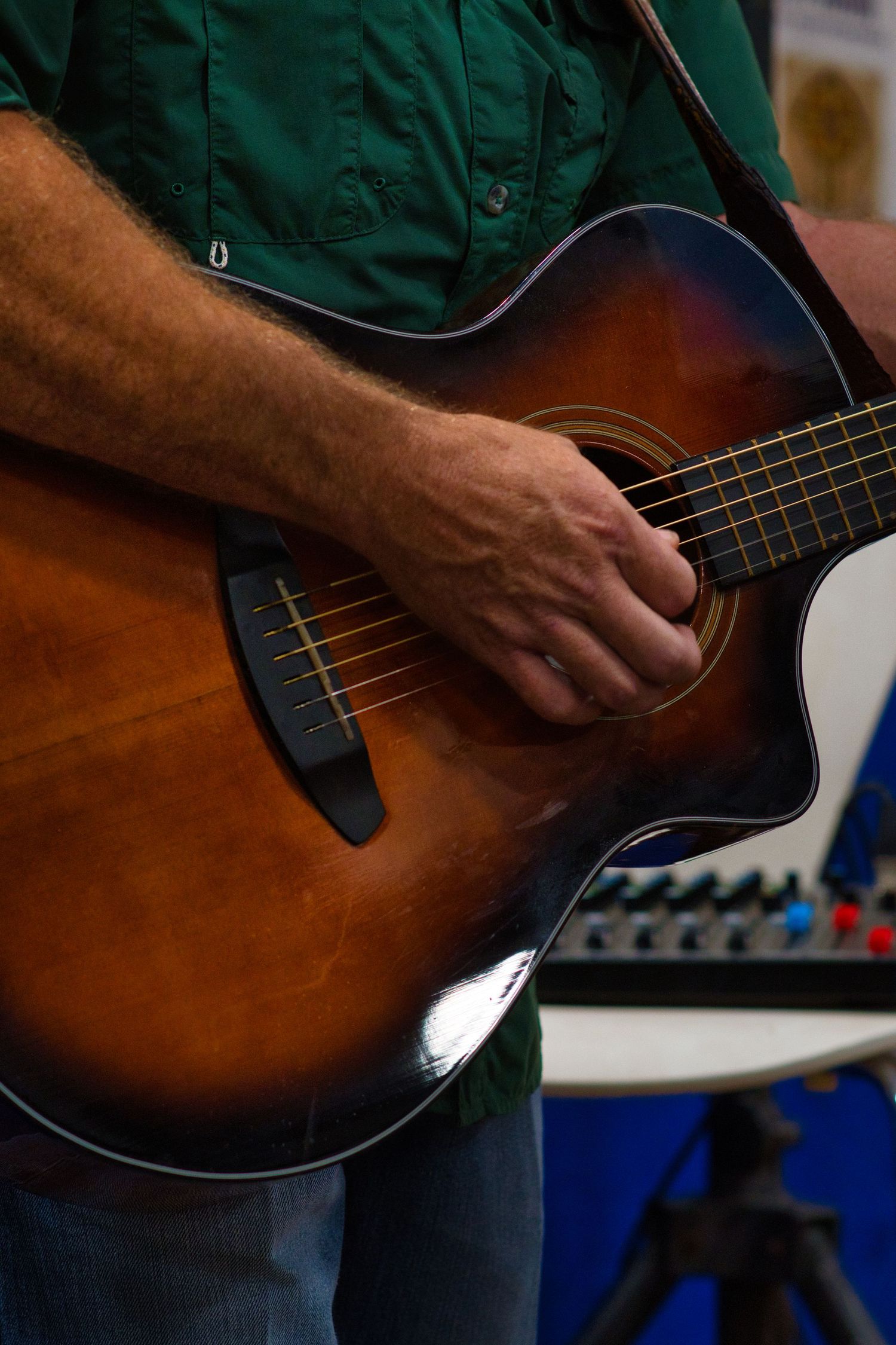 Close-up of hands playing an acoustic guitar with sunburst finish.