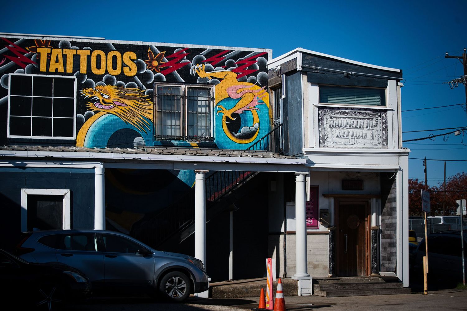 Colorful dragon artwork adorns the facade of a tattoo shop storefront.