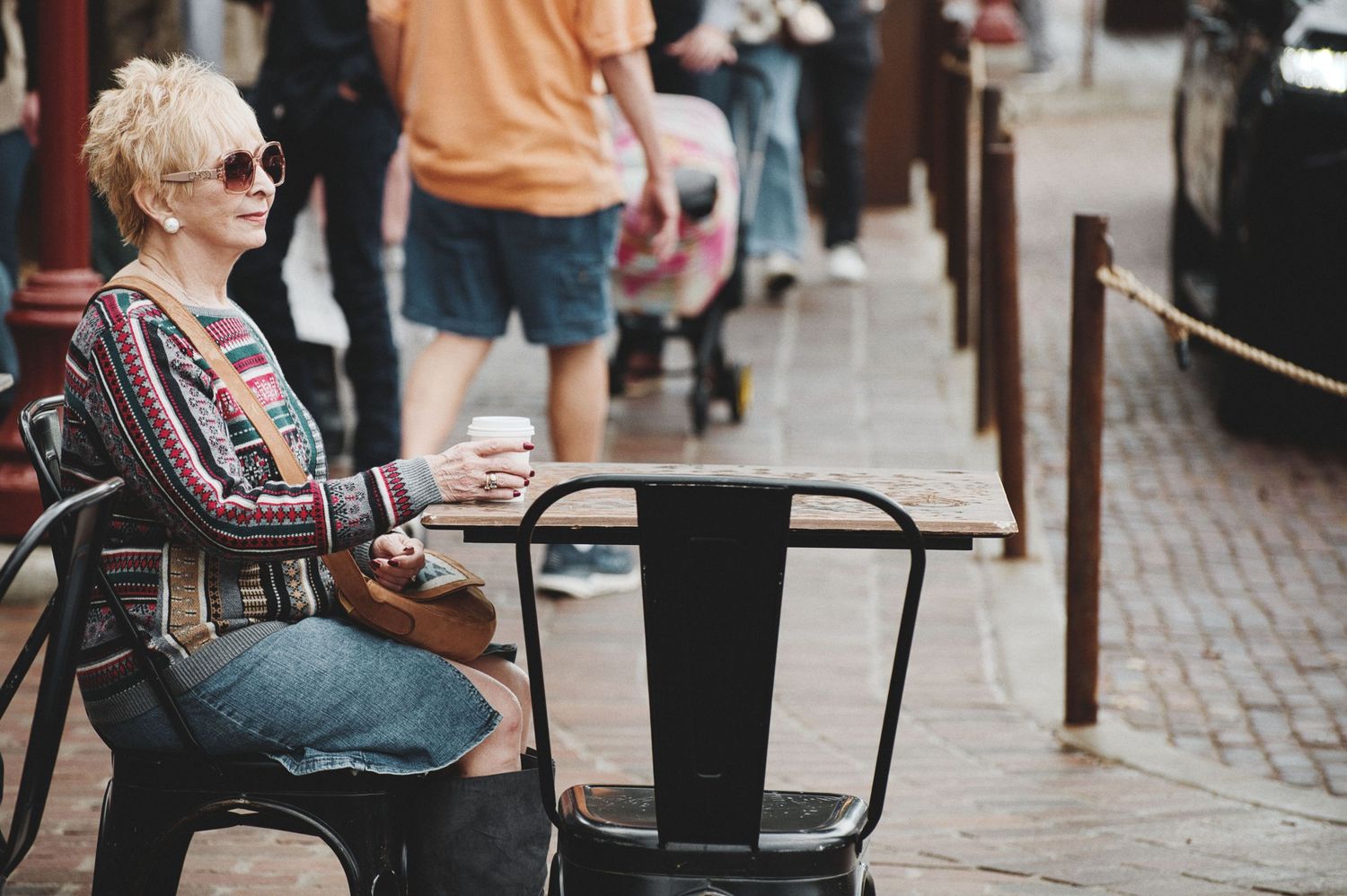 A casual outdoor cafe scene with metal chairs and brick pavement.
