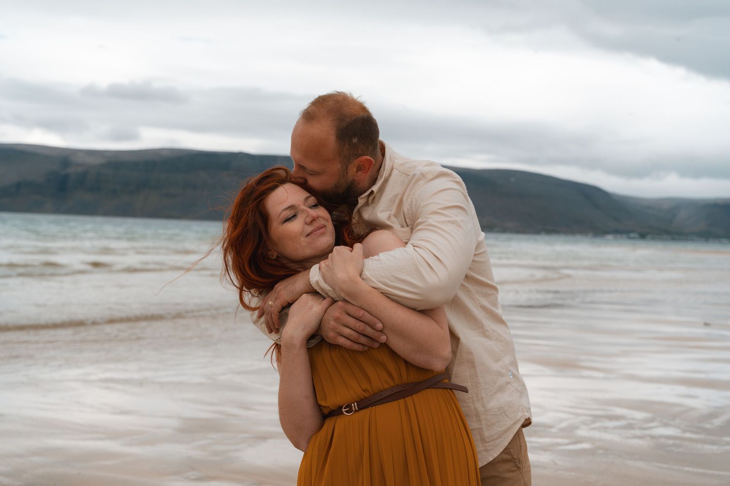 Natalie and Slavek embracing with fjord cliffs in the background