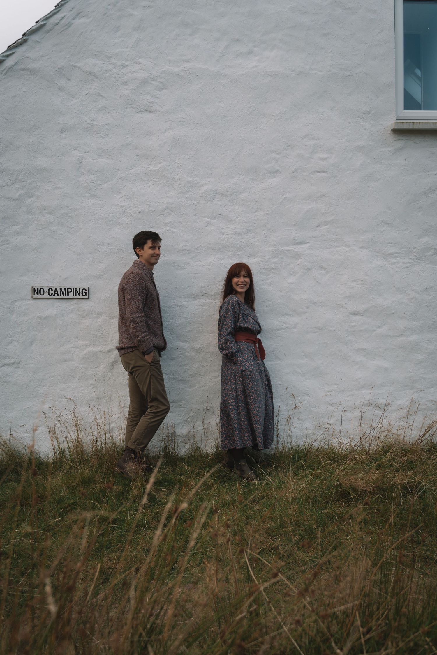 Laughing couple spinning in a field during engagement-style session