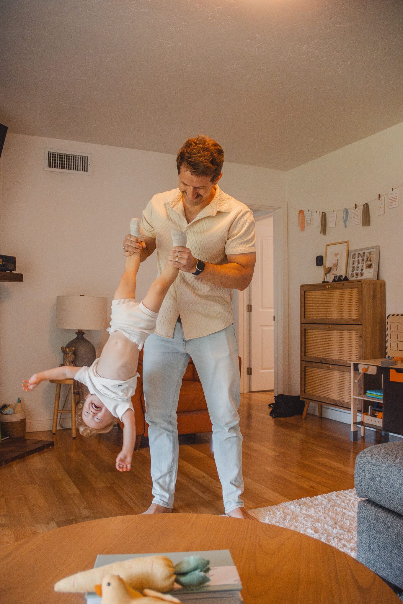 Playing and having fun in the living room with light hardwood floors and wooden furniture.