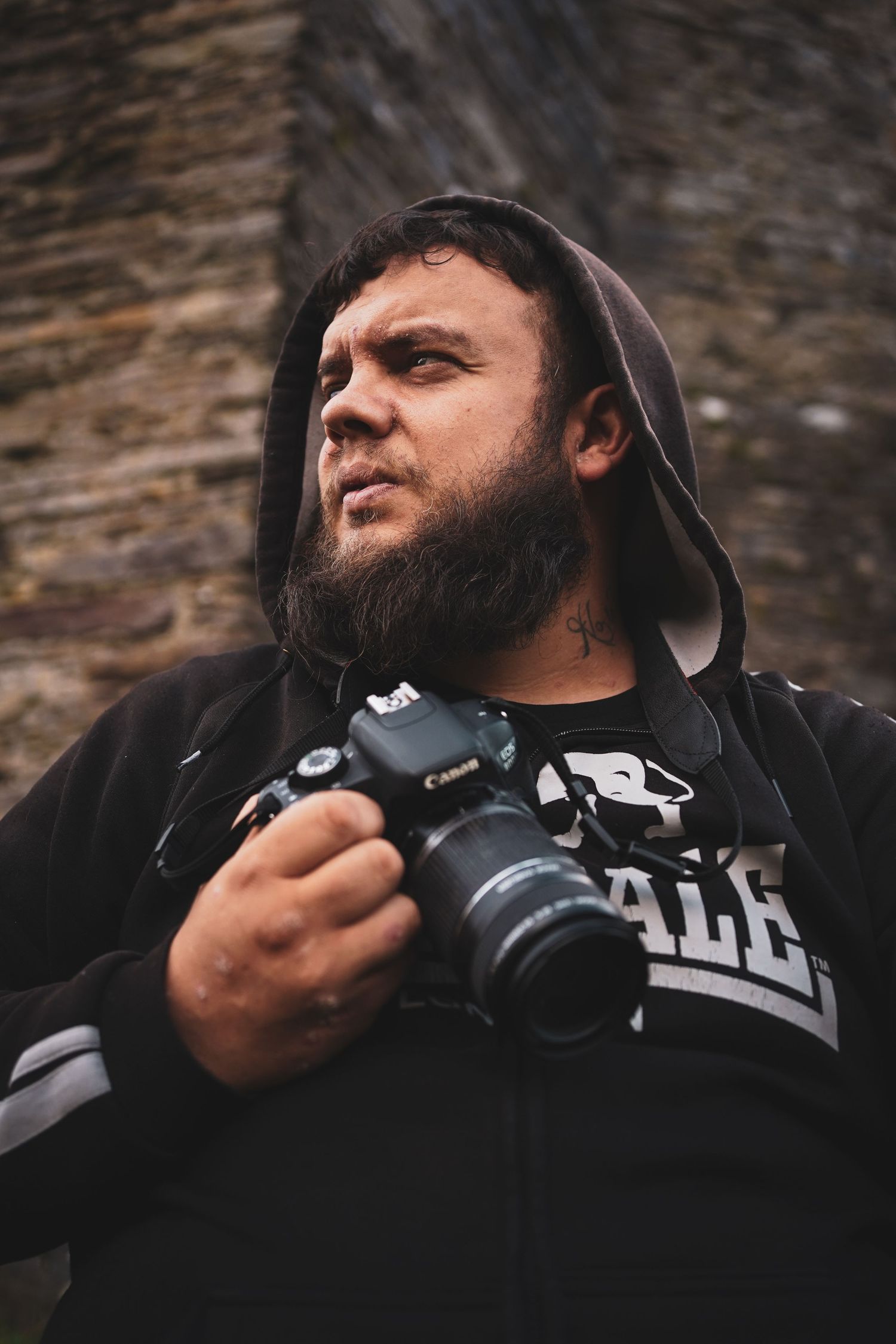 Close-up sequence of a photographer examining a DSLR camera against a stone wall backdrop.