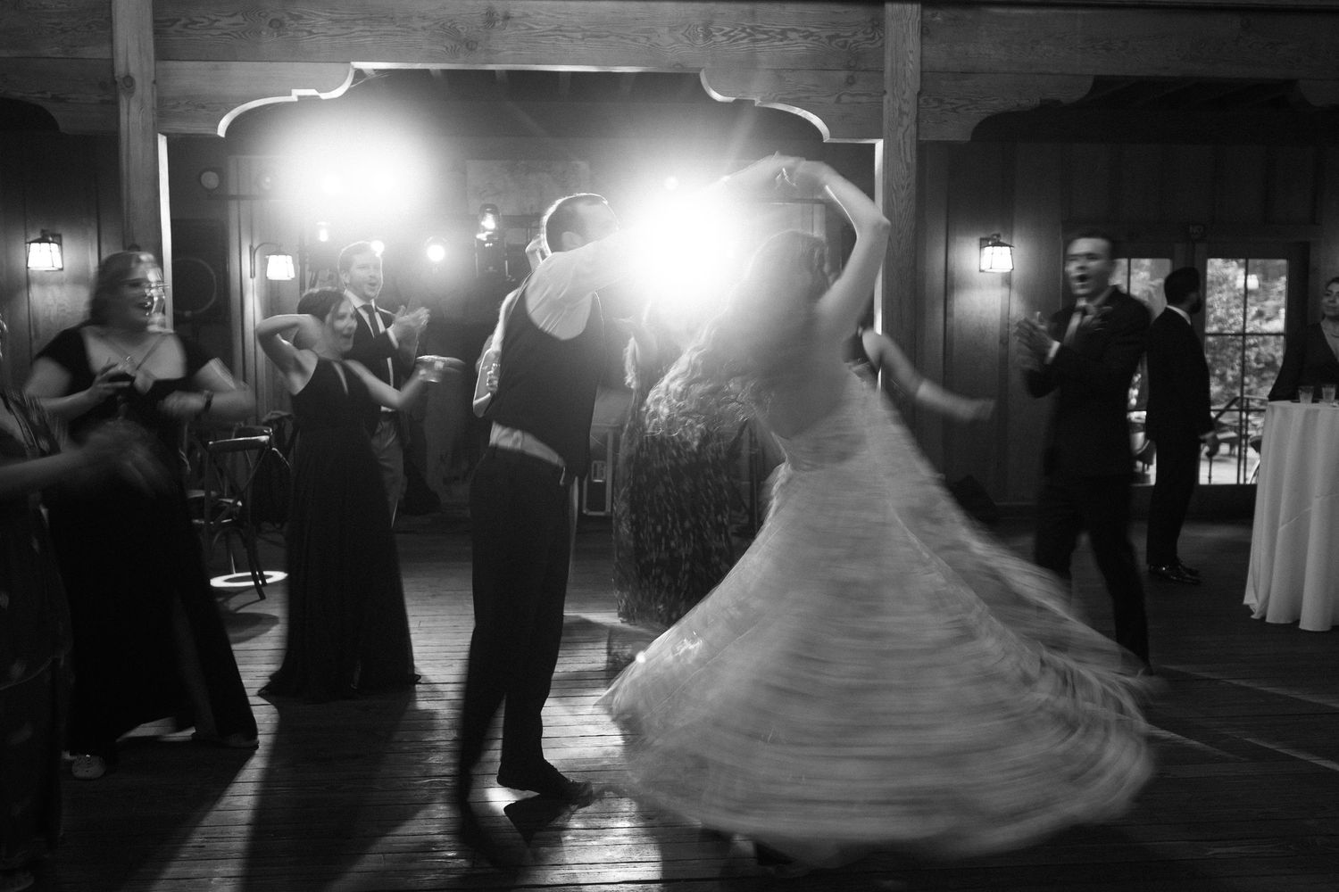 Black and white photo of a couple dancing at an elegant reception as guests watch from the sides of a ballroom.