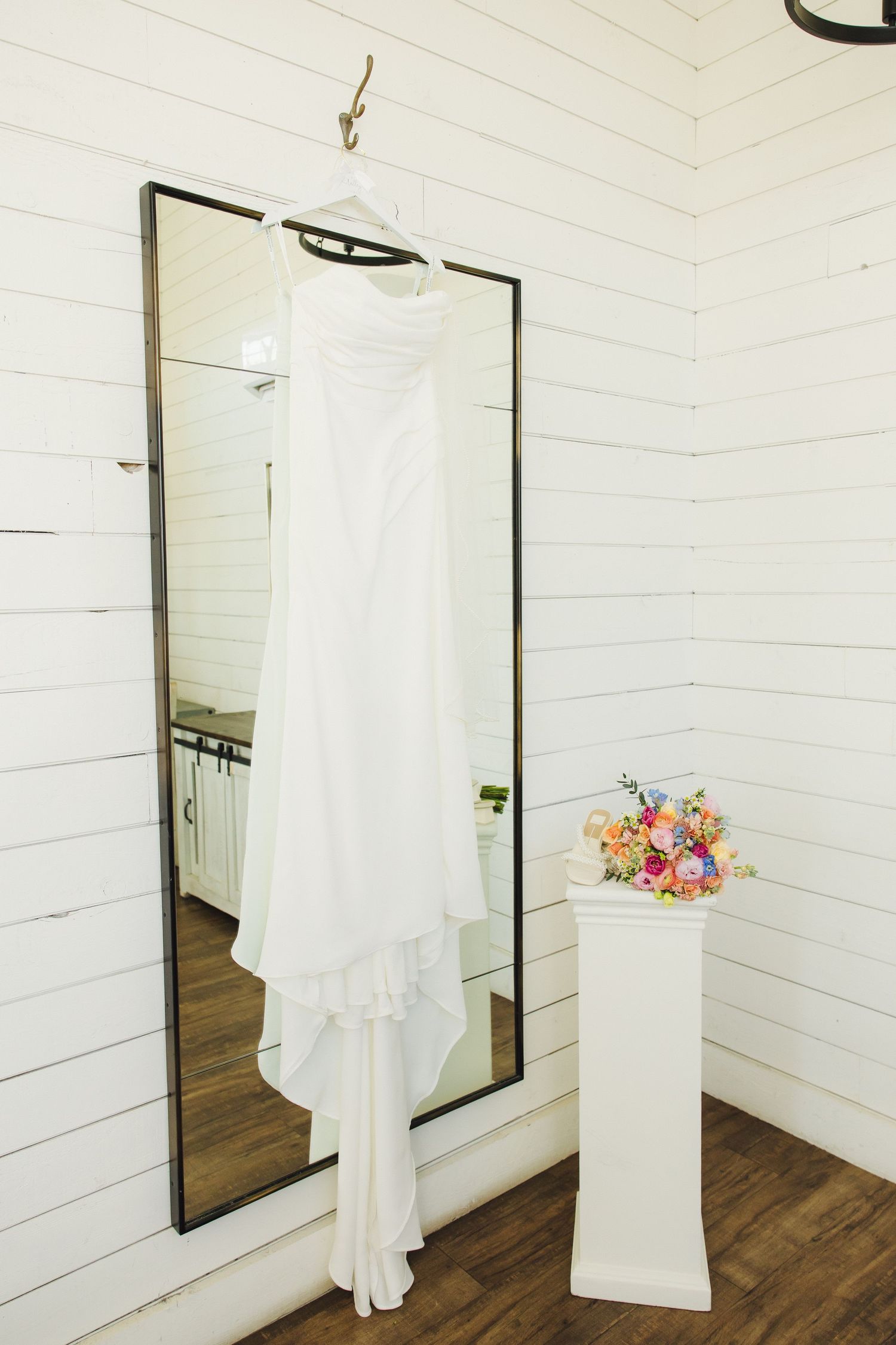 White shiplap walls with dark-framed mirrors and changing room curtains in a rustic boutique space.