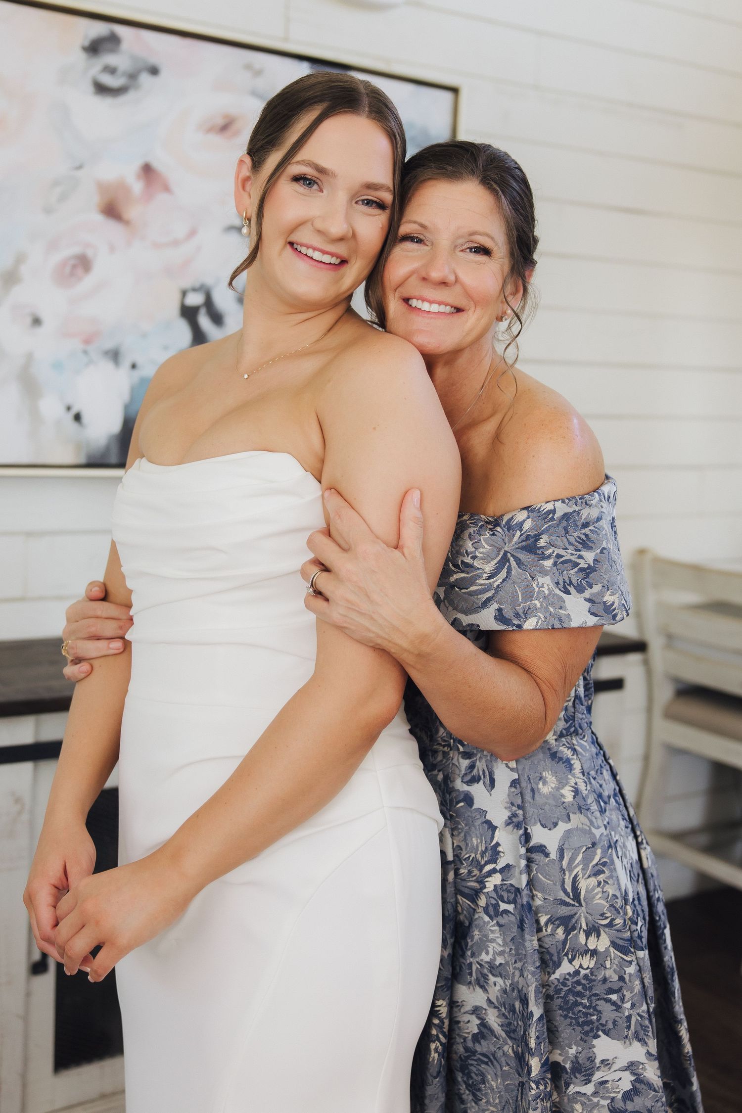 A sequence showing joyful candid moments between two people dressed in a white gown and blue floral dress at an indoor event.