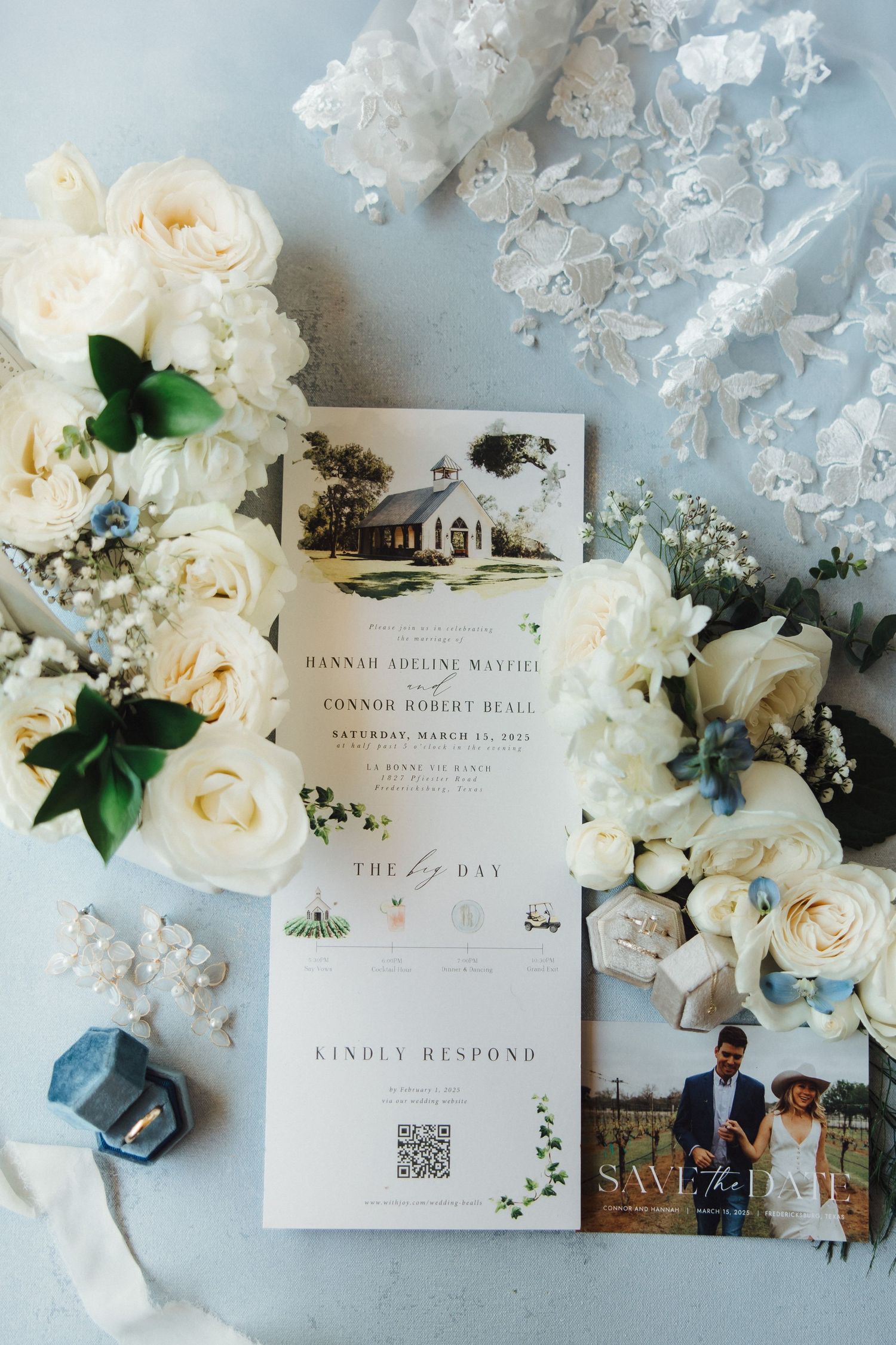 Elegant wedding invitation suite with white roses, delicate lace, and a blue ring box on light gray background.