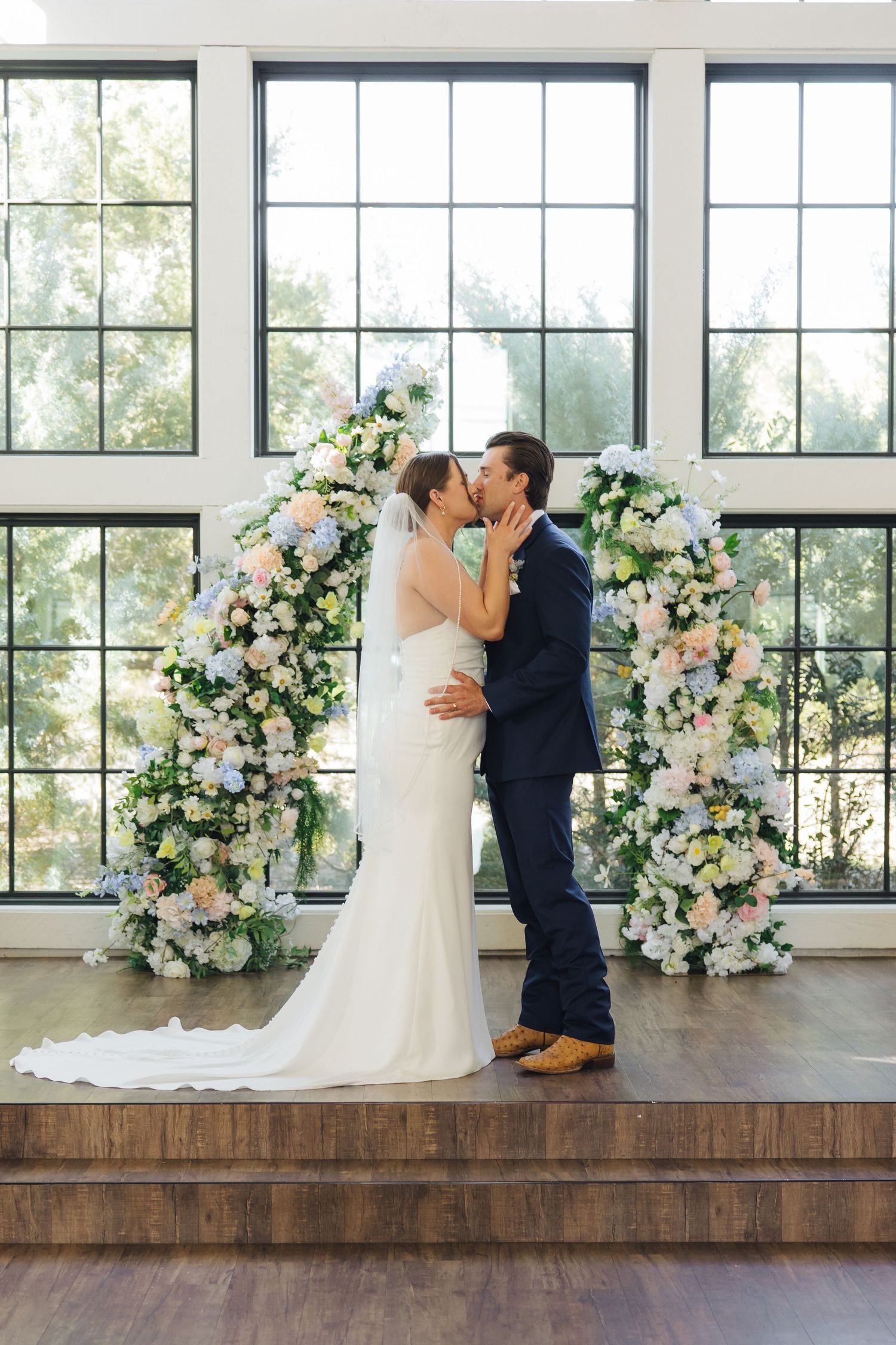 A romantic wedding sequence showing a couple sharing their first dance in a modern venue with floral arch arrangements.