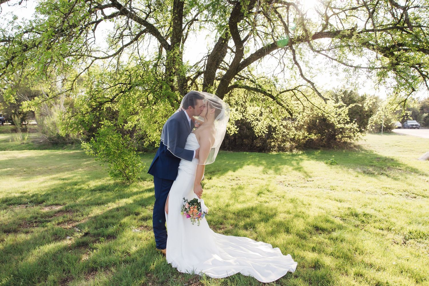 Romantic wedding photos taken at golden hour under flowering spring trees in a beautiful outdoor garden setting.