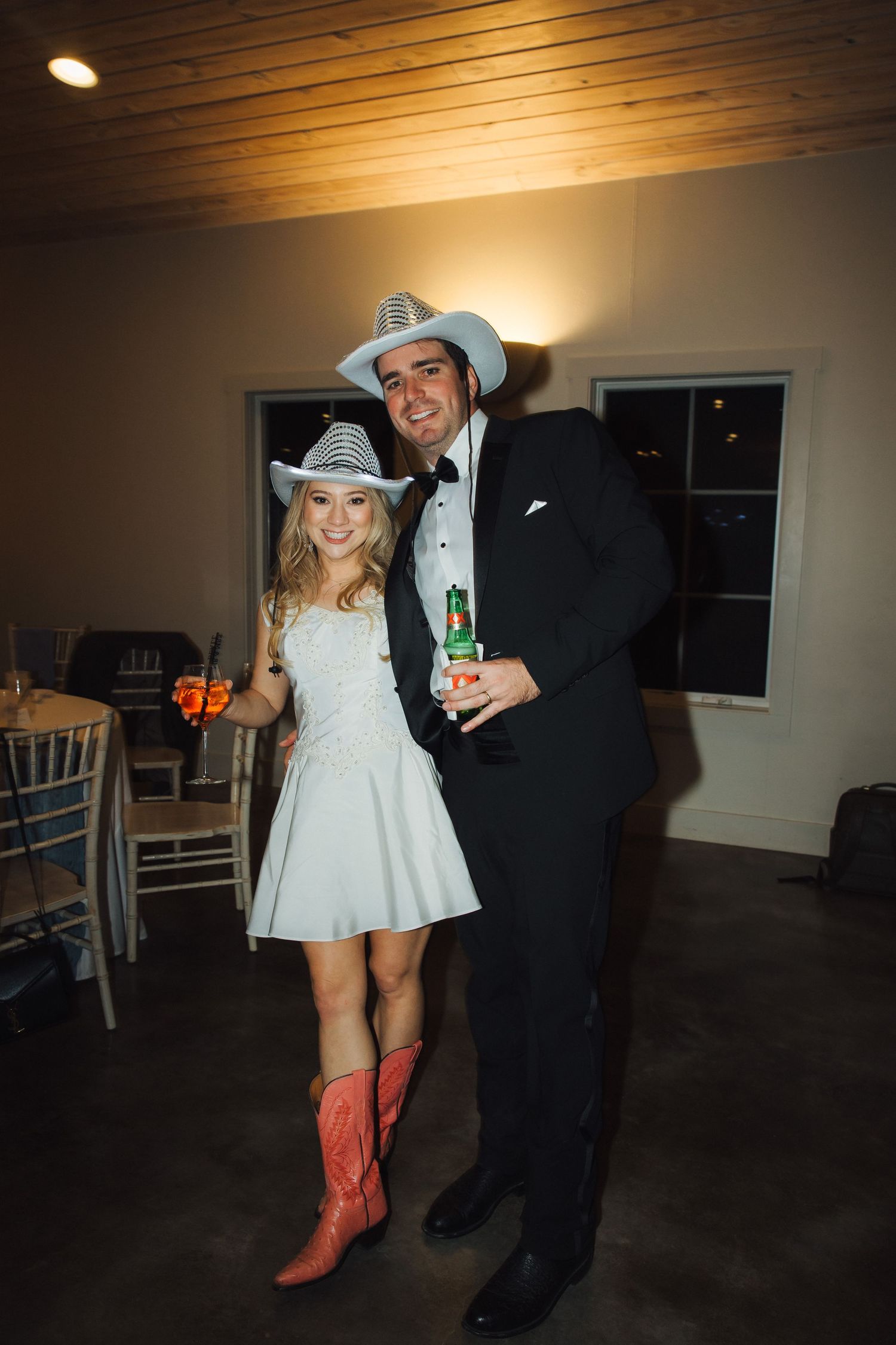 Wedding reception scene with cowboy boots and party attire in a dimly lit venue with warm lighting.