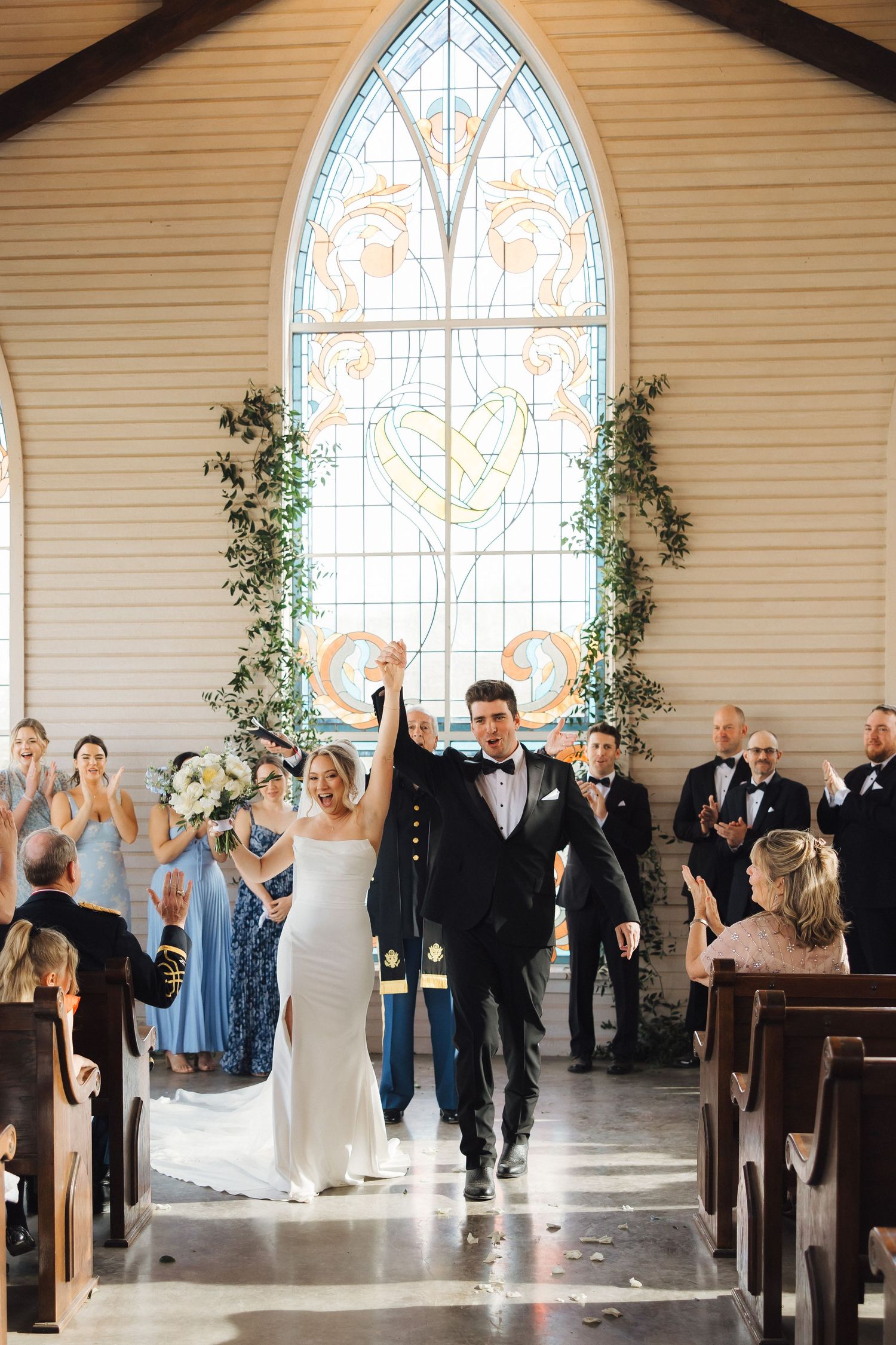 A joyful celebration inside a chapel with a beautiful stained glass window and ivy-adorned walls.