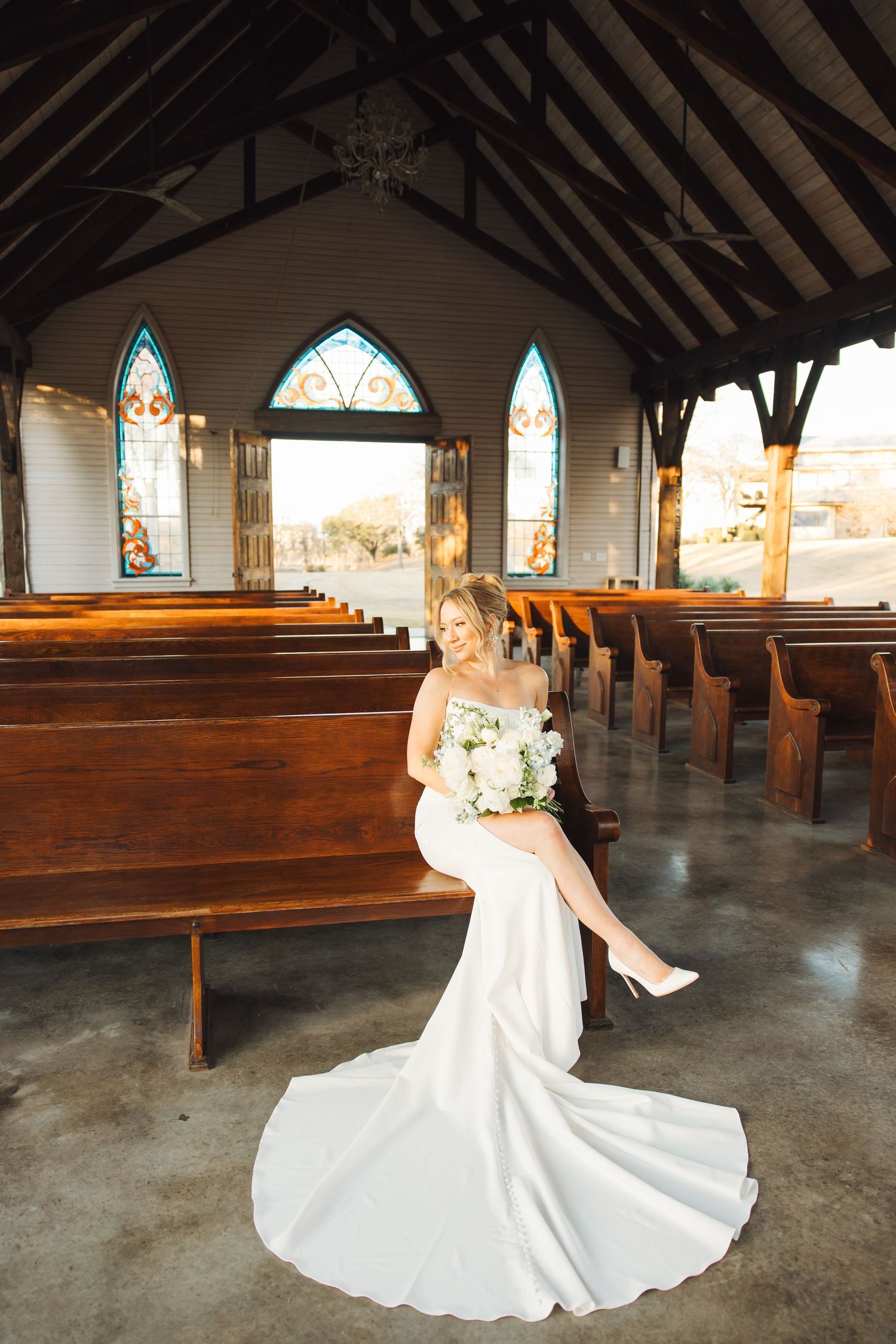 A wedding dress is elegantly displayed in various poses inside a rustic church sanctuary with wooden pews and stained glass windows.
