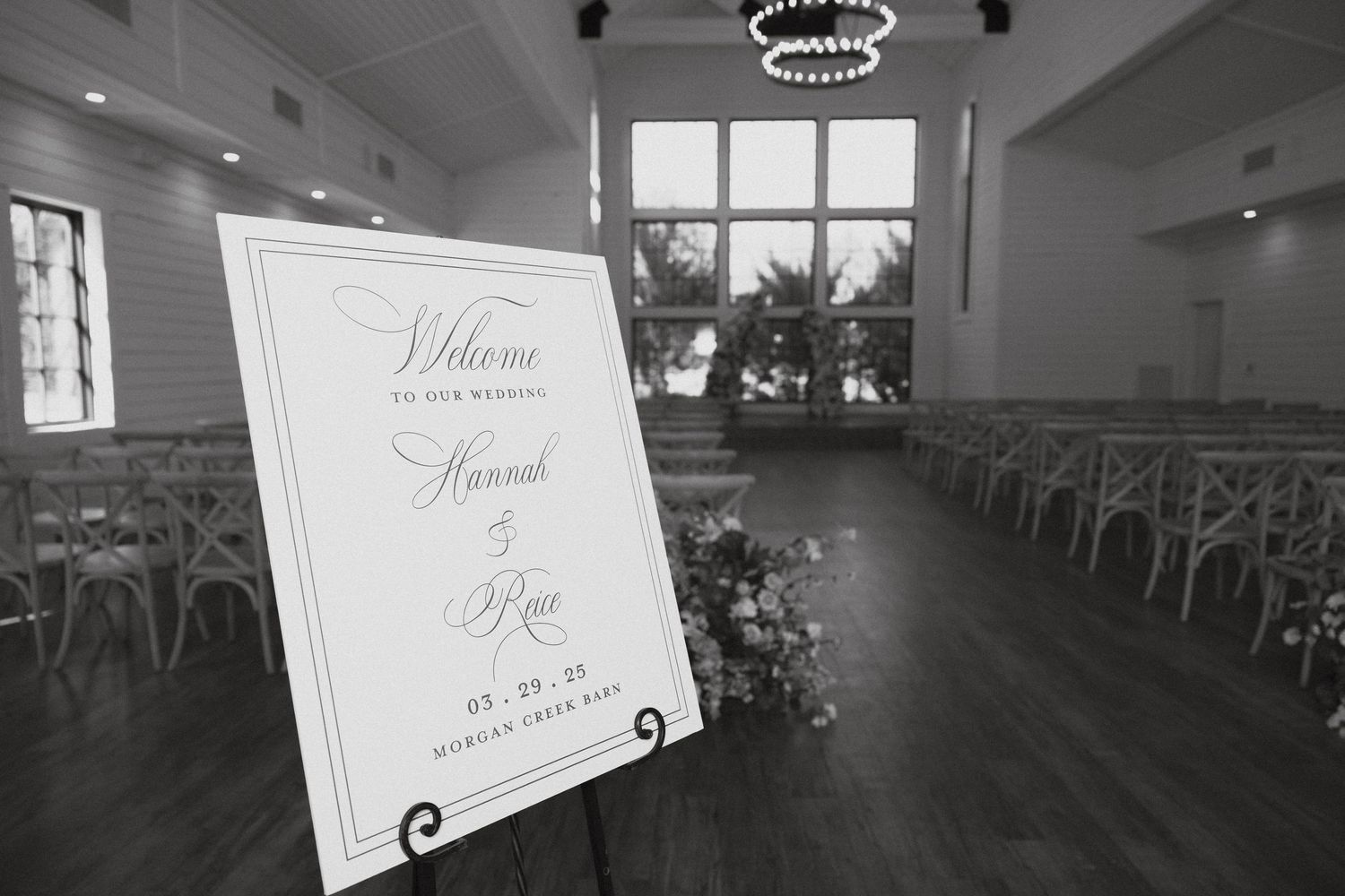 Interior view of an elegant white reception hall with ornate chandeliers and large windows letting in natural light.