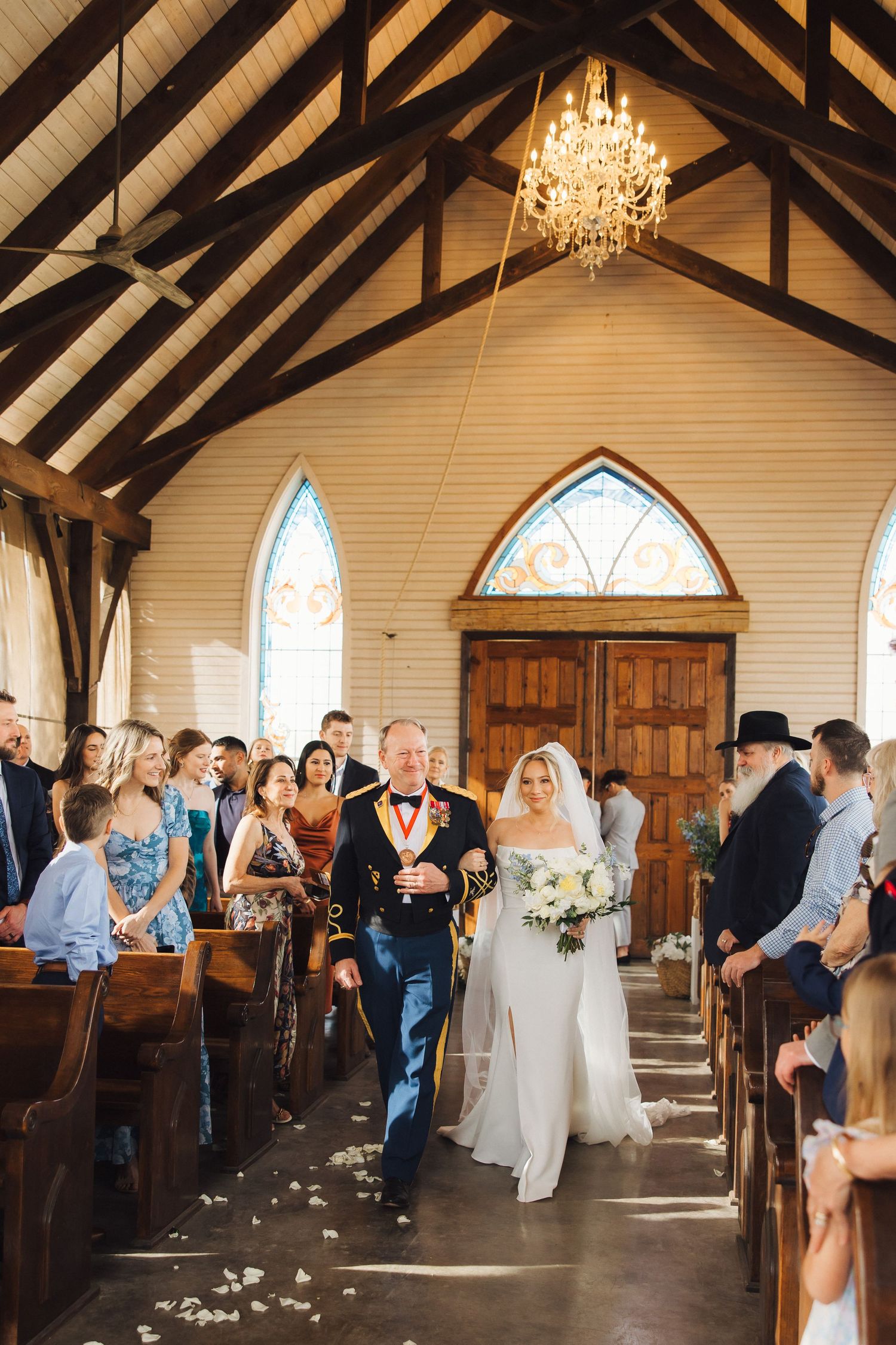 Wedding ceremony in progress inside a charming chapel with exposed wooden beams and crystal chandeliers.