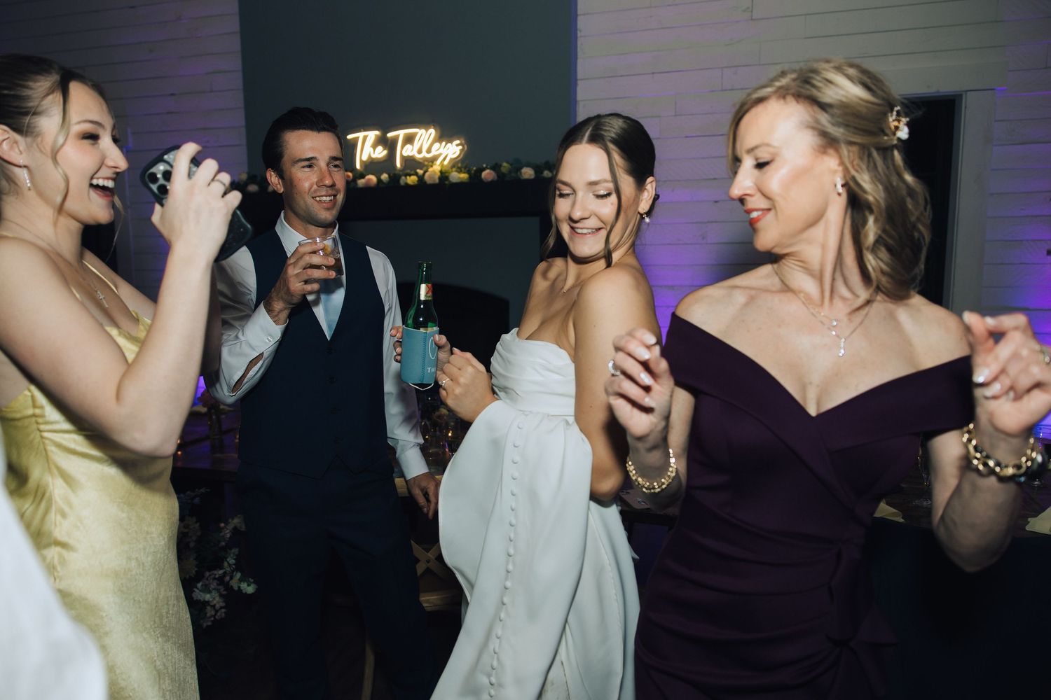 Guests dance and celebrate together on a dark dance floor at an evening wedding reception event.
