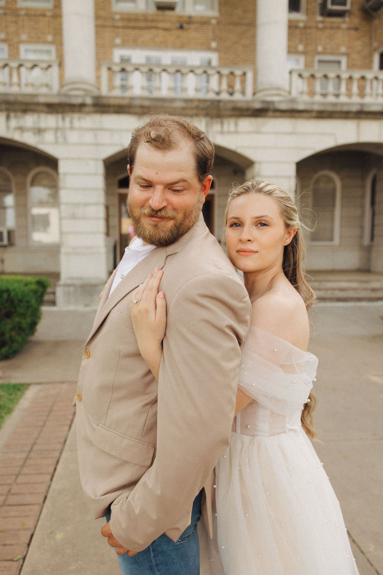A couple in wedding attire embraces in front of a historic building in multiple romantic poses.