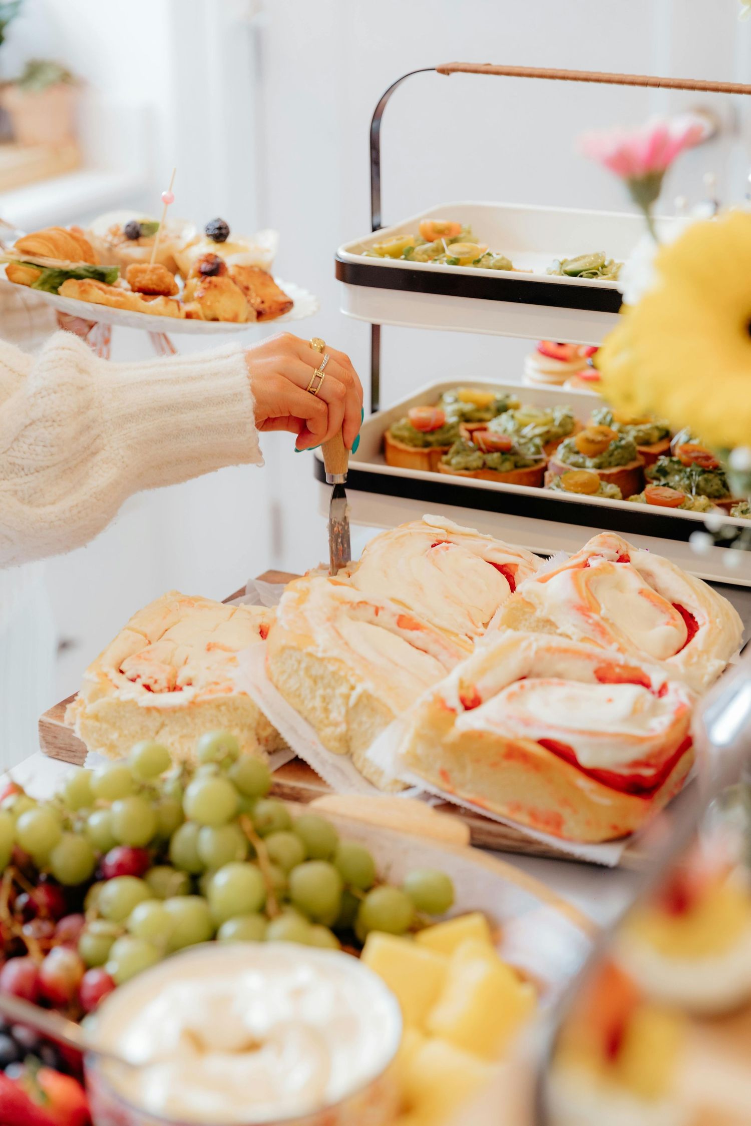 A catered buffet spread featuring sandwiches, fresh fruit, and appetizers arranged on white serving platters.