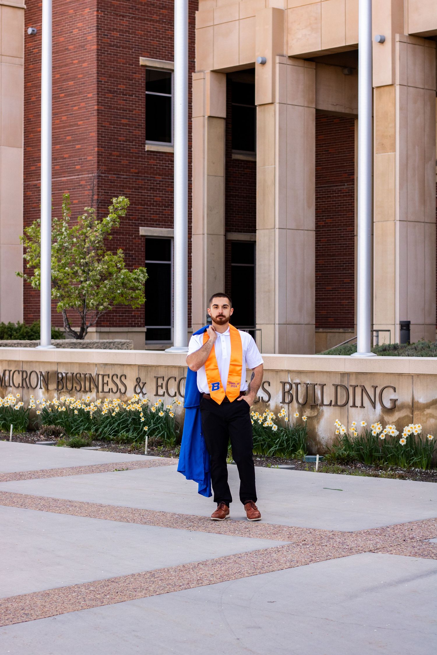 a grad posing in front of a Business Building on campus