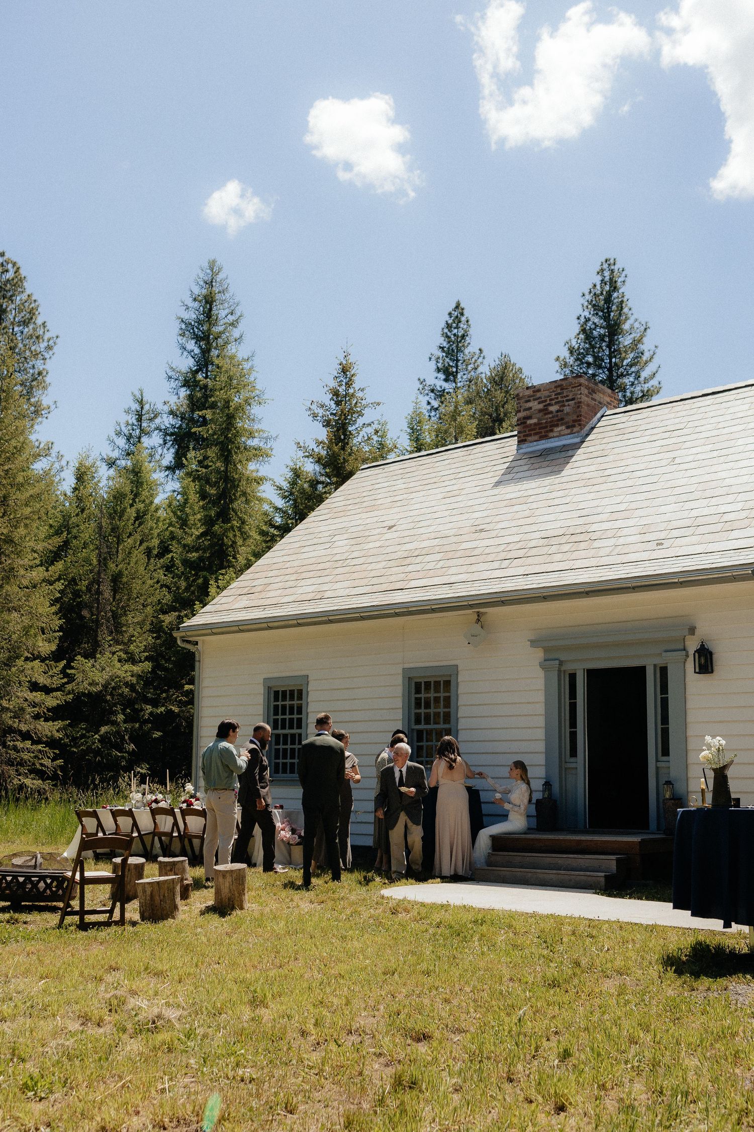 Small white countryside church with rustic wooden steps and evergreen trees in the background on a sunny summer day.